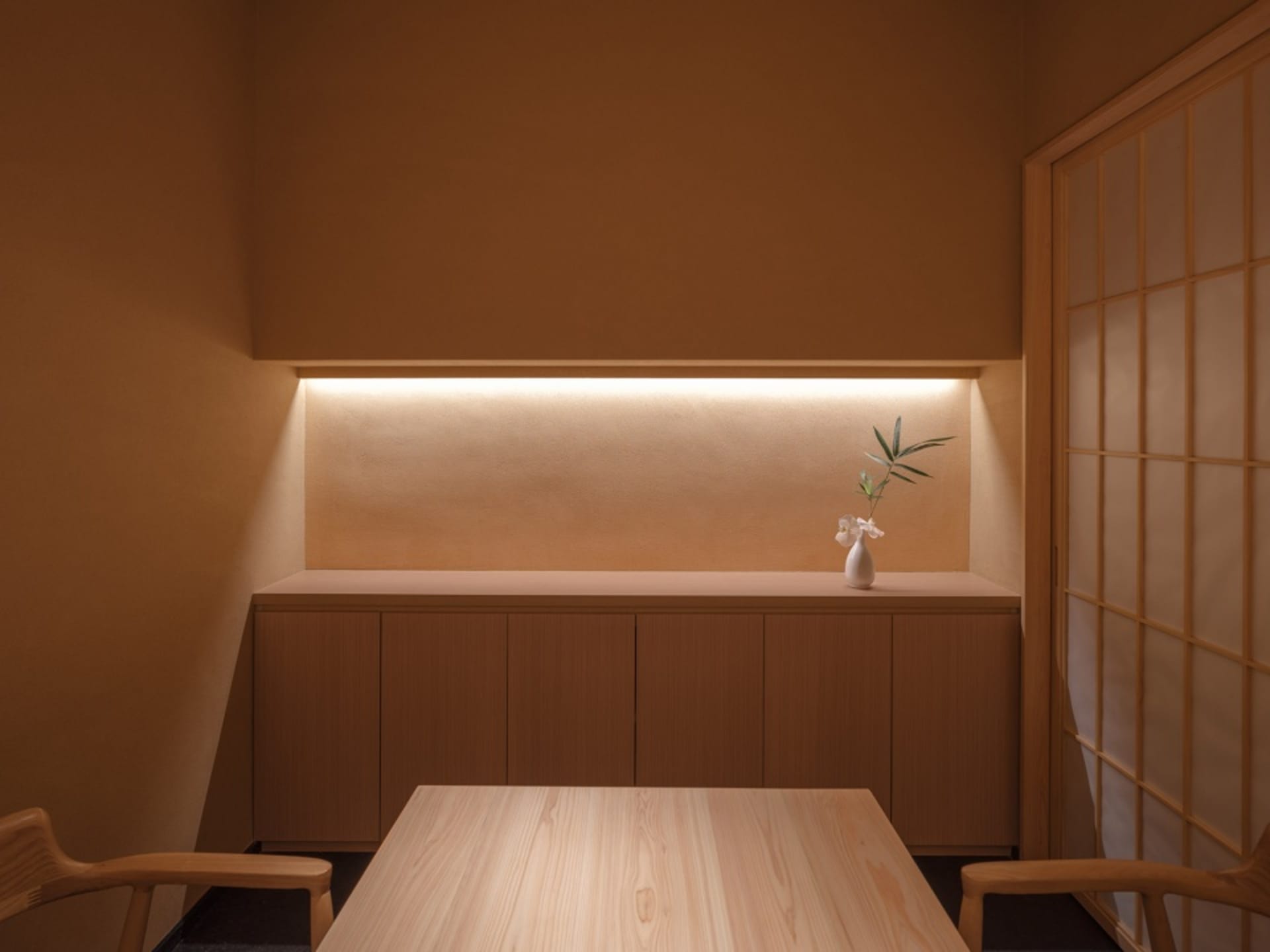 Minimalist design with a small space, wooden table, and ceramic vase with flowers.