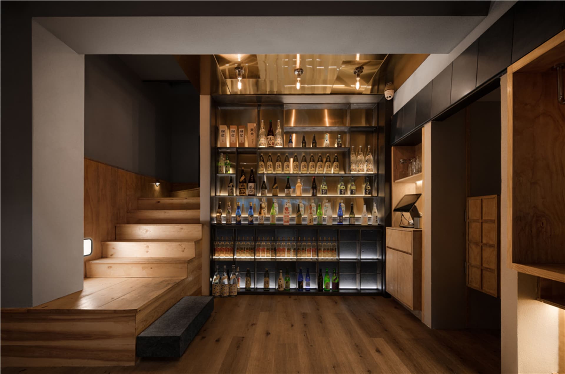 A modern bar interior with wooden shelves displaying a variety of bottles.