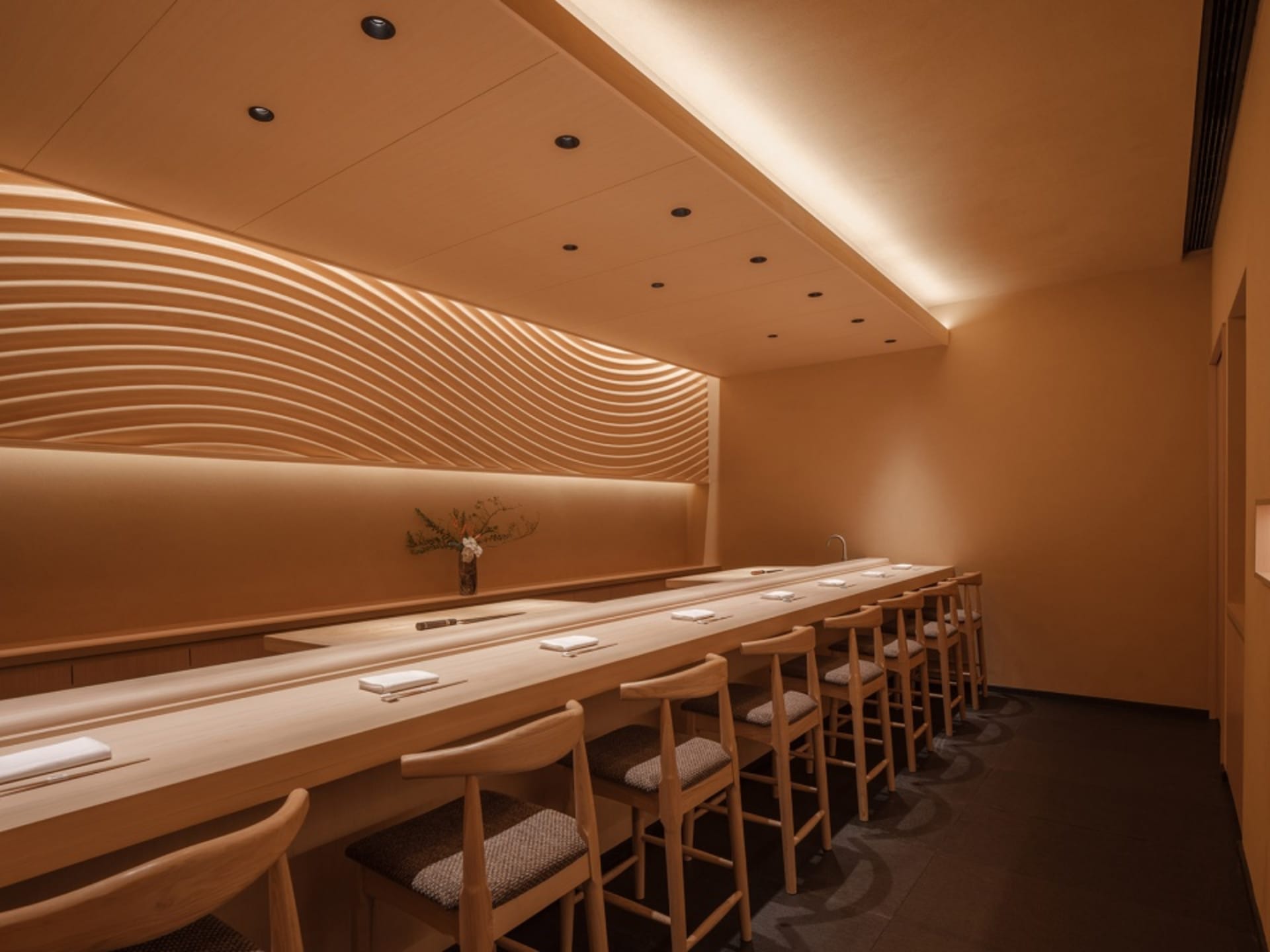 Modern restaurant interior with wooden seating, terrazzo counter, and geometric wave design