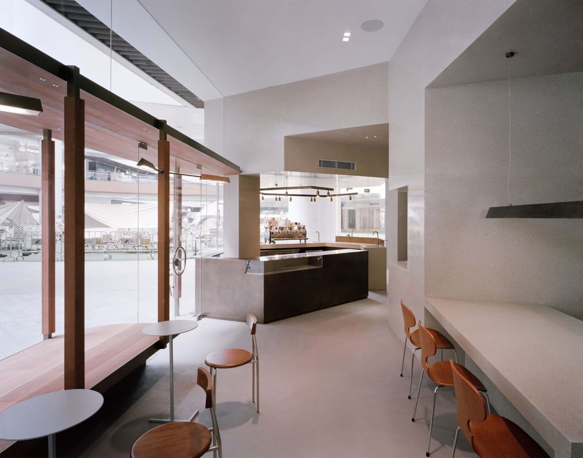 A sleek, minimalist coffee shop designed with concrete and wood materials, featuring a contemporary interior layout.