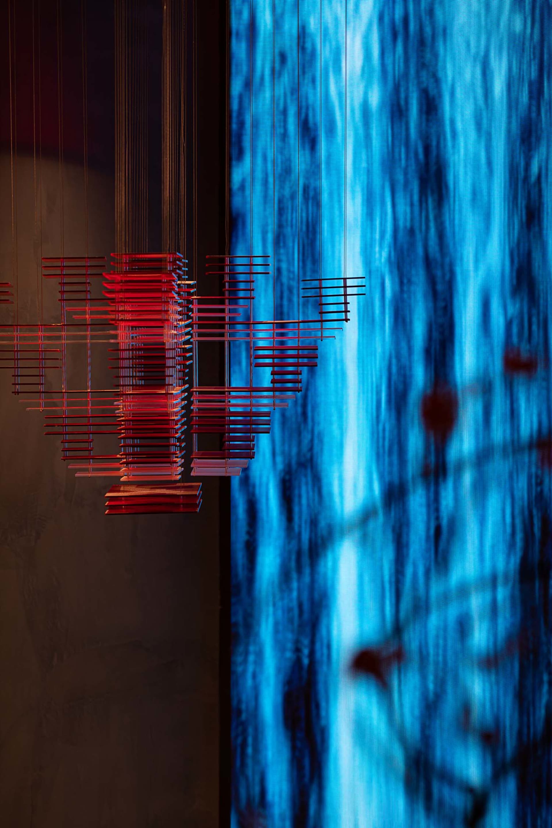 Minimalist art installation featuring metallic rods on a blue background.