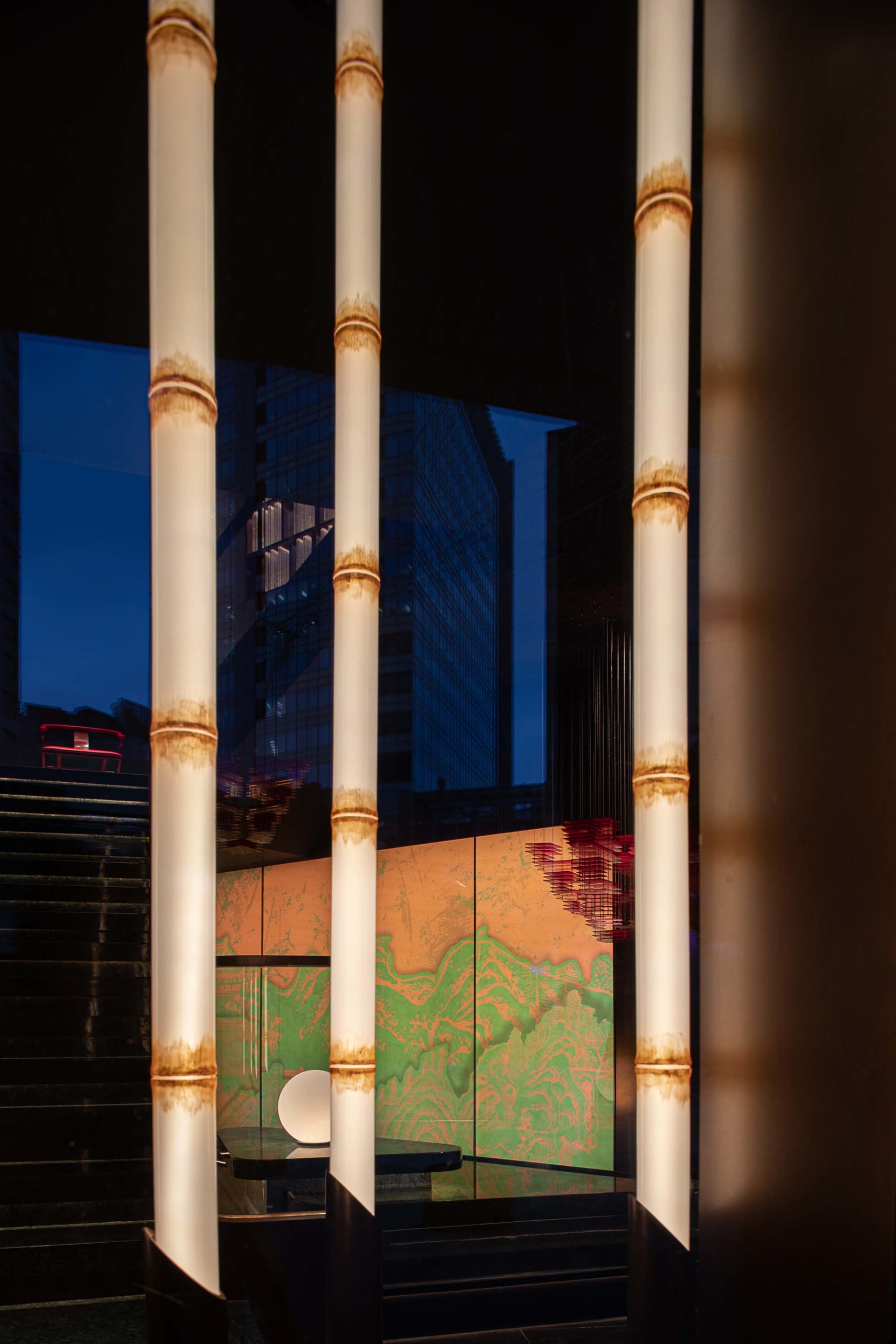 The interior of a modern lobby with glass pillars and a colorful mural on the wall.