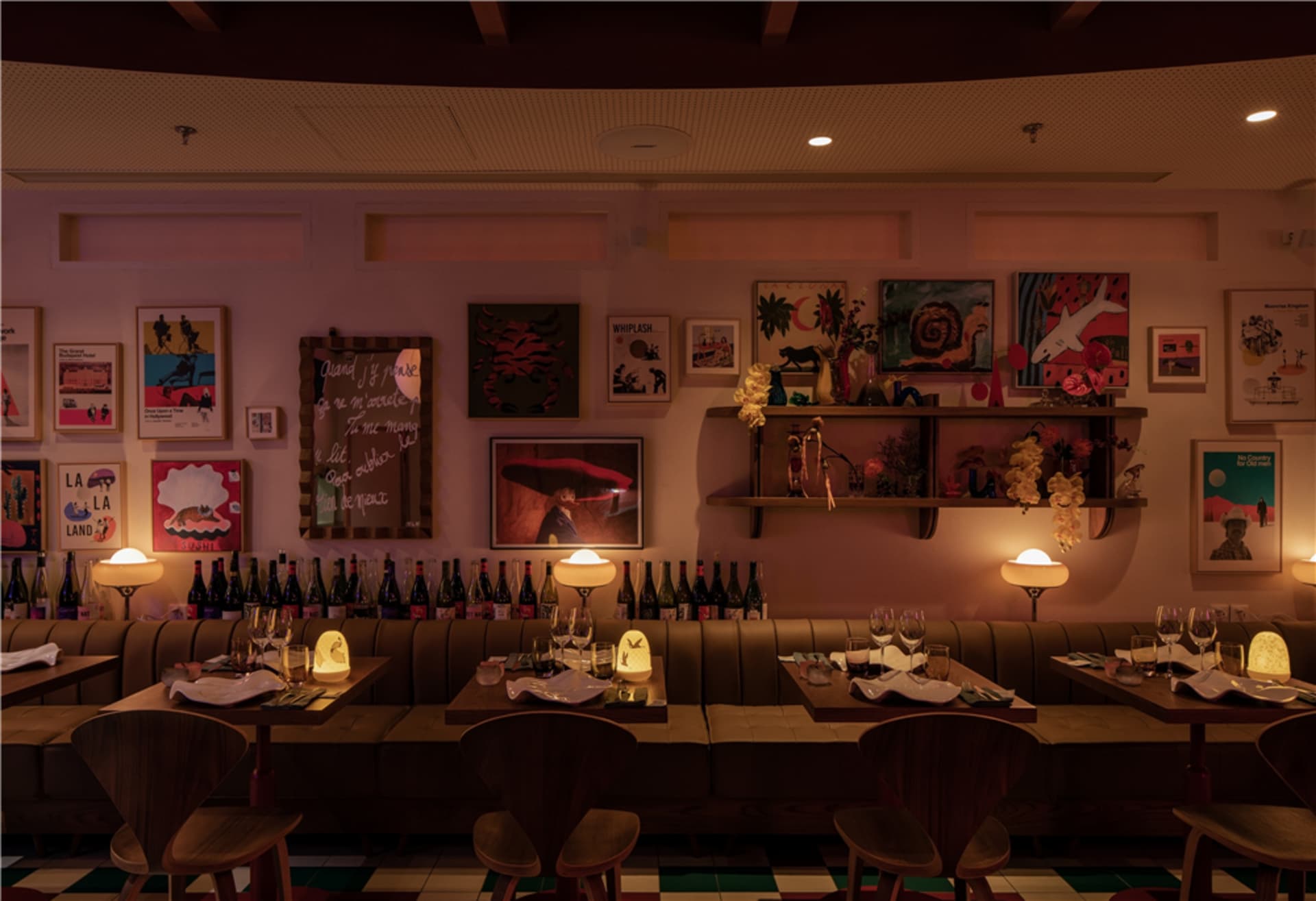 A cozy restaurant interior with a mid-century modern aesthetic featuring comfortable seating, artful wall decor, and a well-o