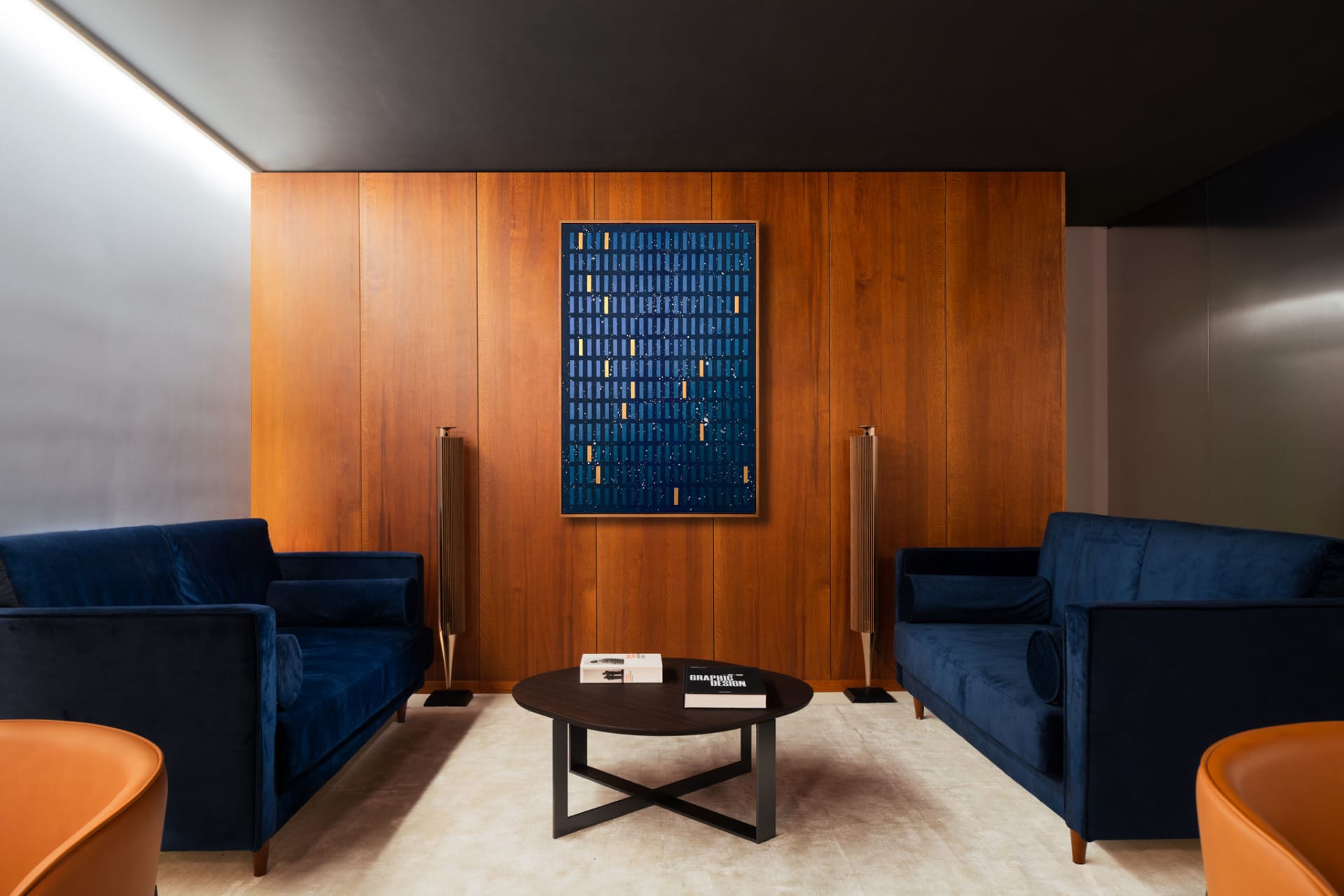 Modern living room furniture with blue sofas and a wooden wall panel