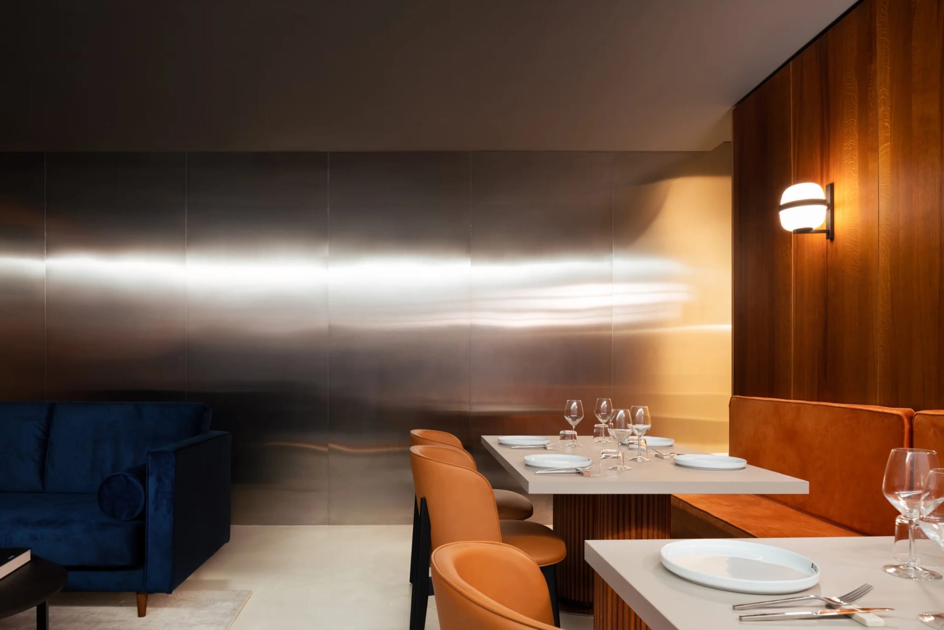 Modern restaurant interior featuring metallic wall panels and wooden paneling.