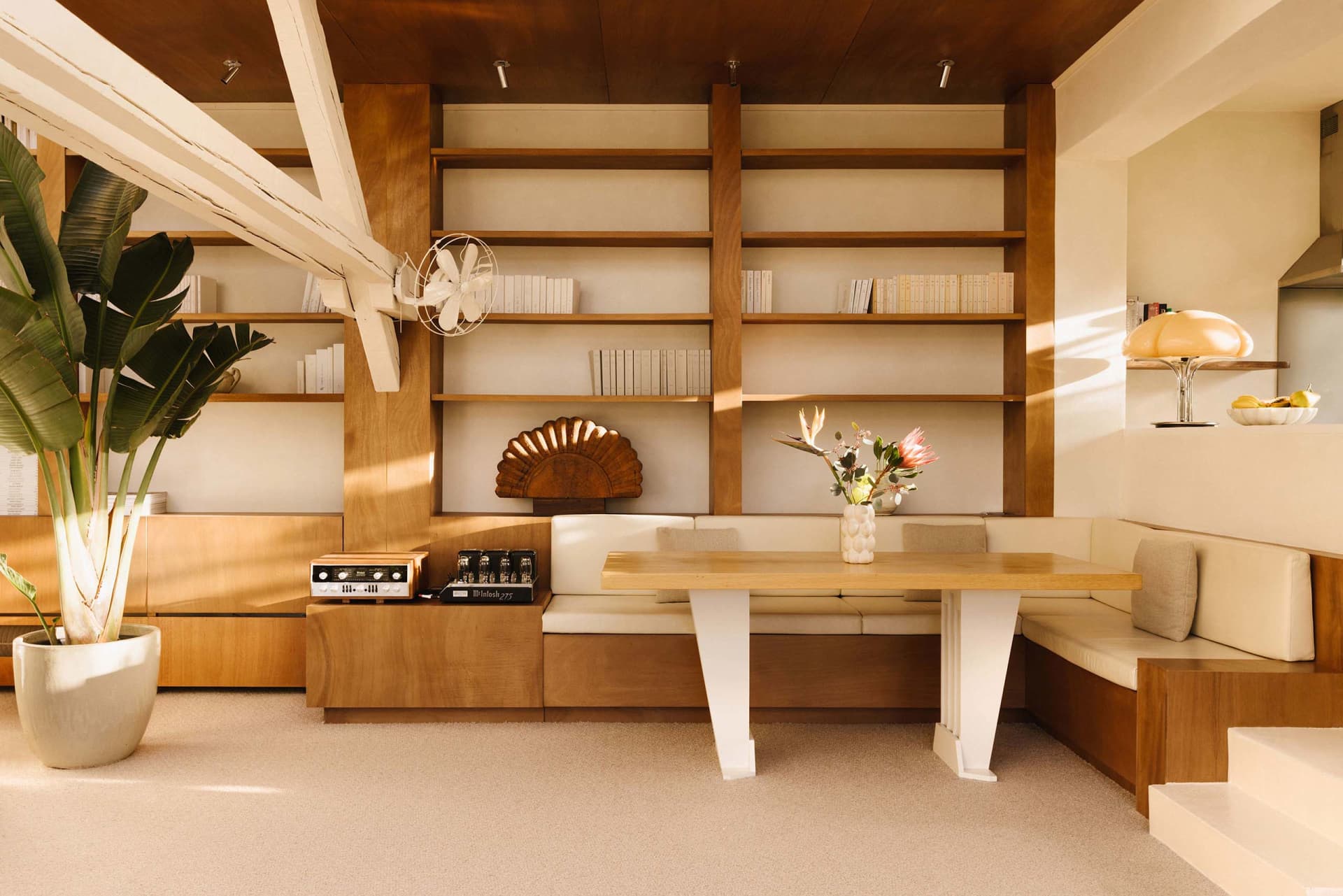 A minimalist living room with wooden furniture, white accents, and a built-in bookshelf.