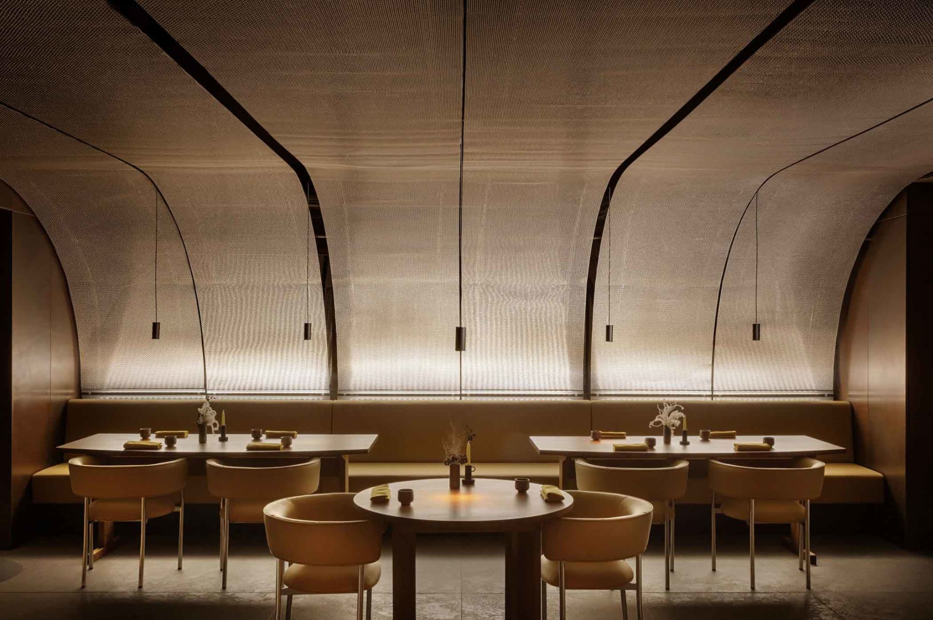 A modern restaurant interior featuring neutral-tones seating and tables adorned with minimalist decor.