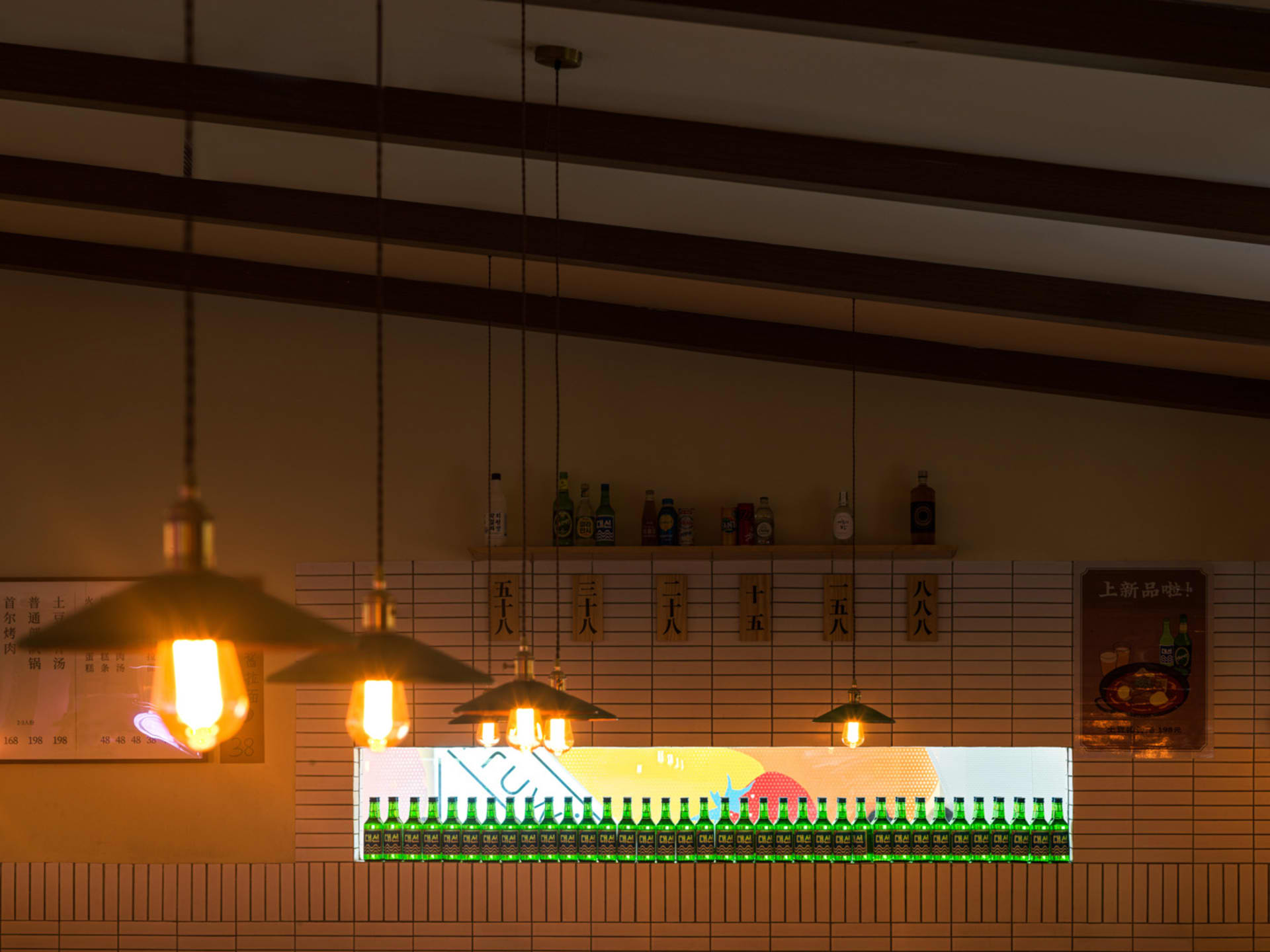 A brick-tiled bar counter with green bottles arranged in a row on the shelf.