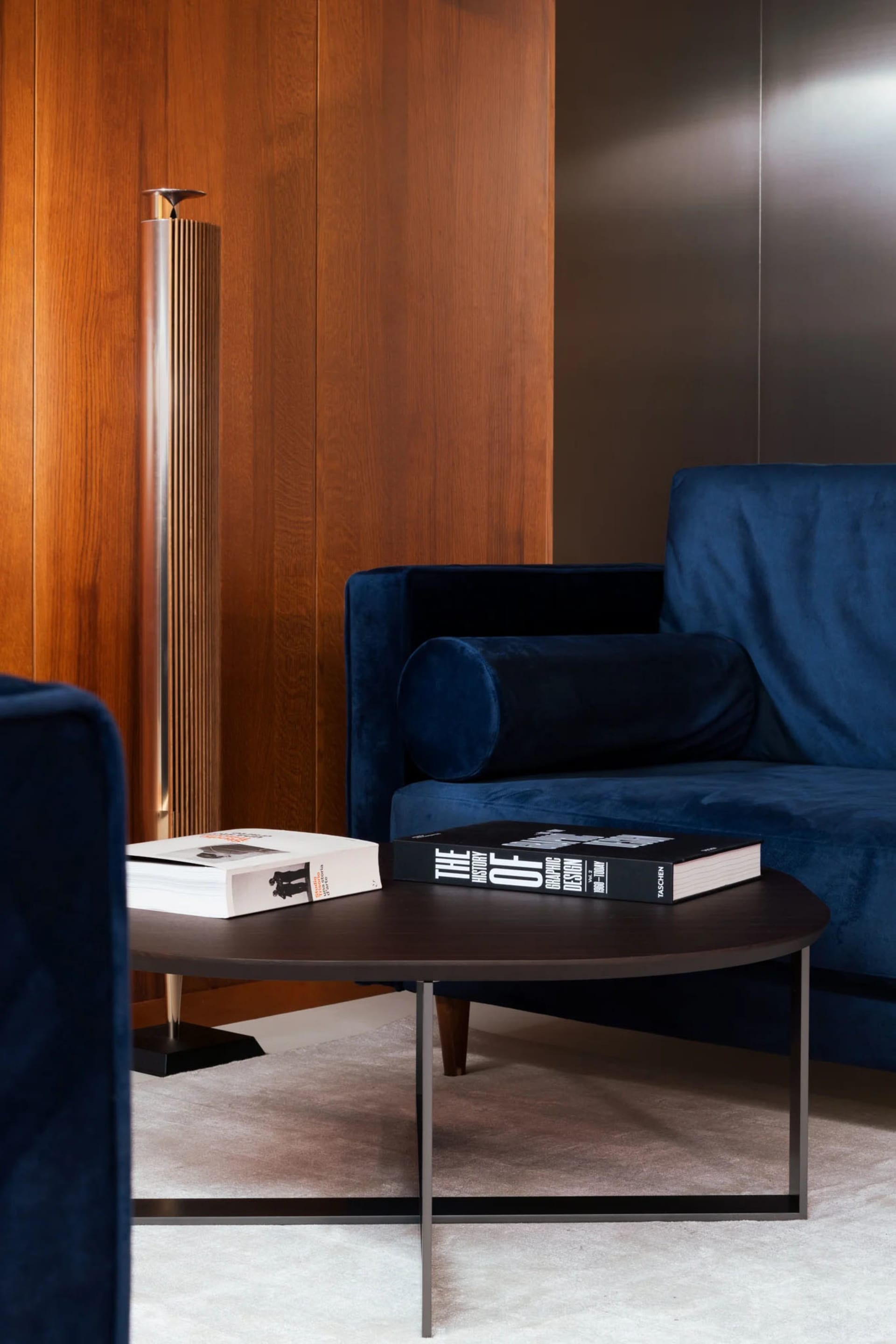 Modern living room featuring a blue velvet couch and a wooden panel wall.