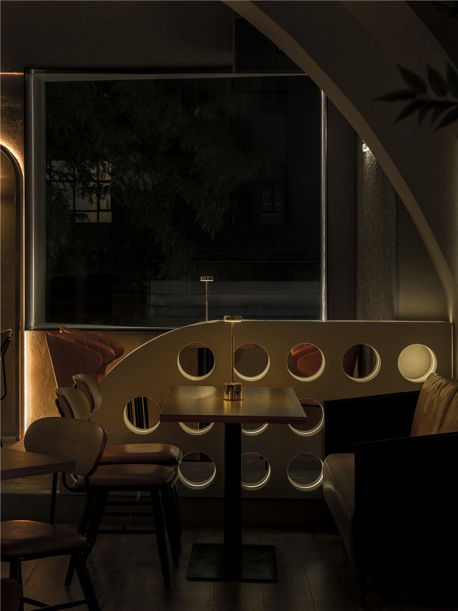 A modern bar interior with a metal wall adorned with circular cutouts, creating a unique and stylish atmosphere.