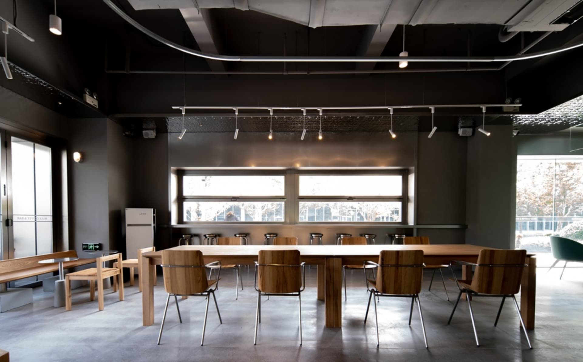 A spacious, minimalist conference room featuring industrial design elements and wood furniture.