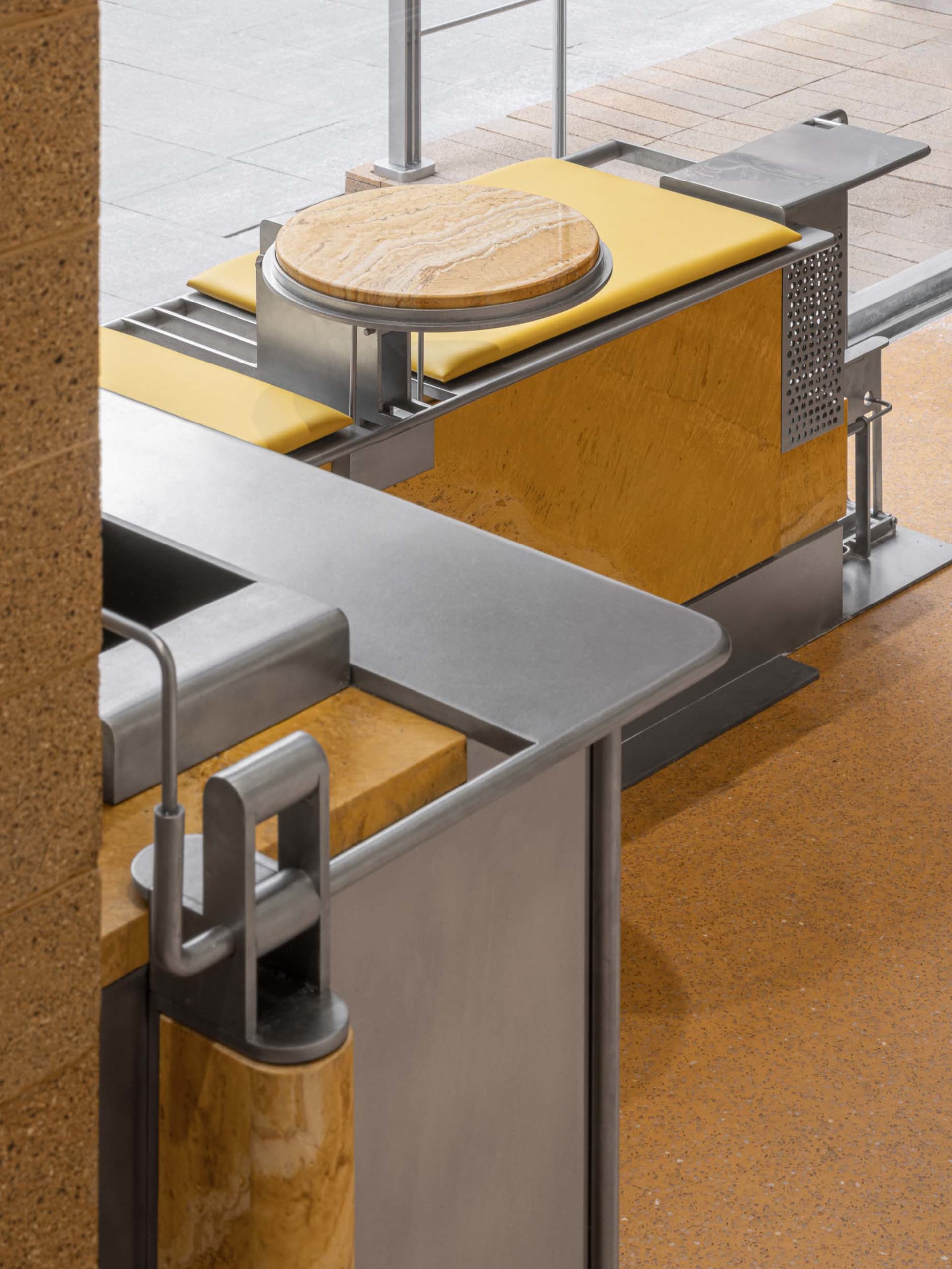 A modern urban furniture piece with metal frame, stone top, and porous composite seat.