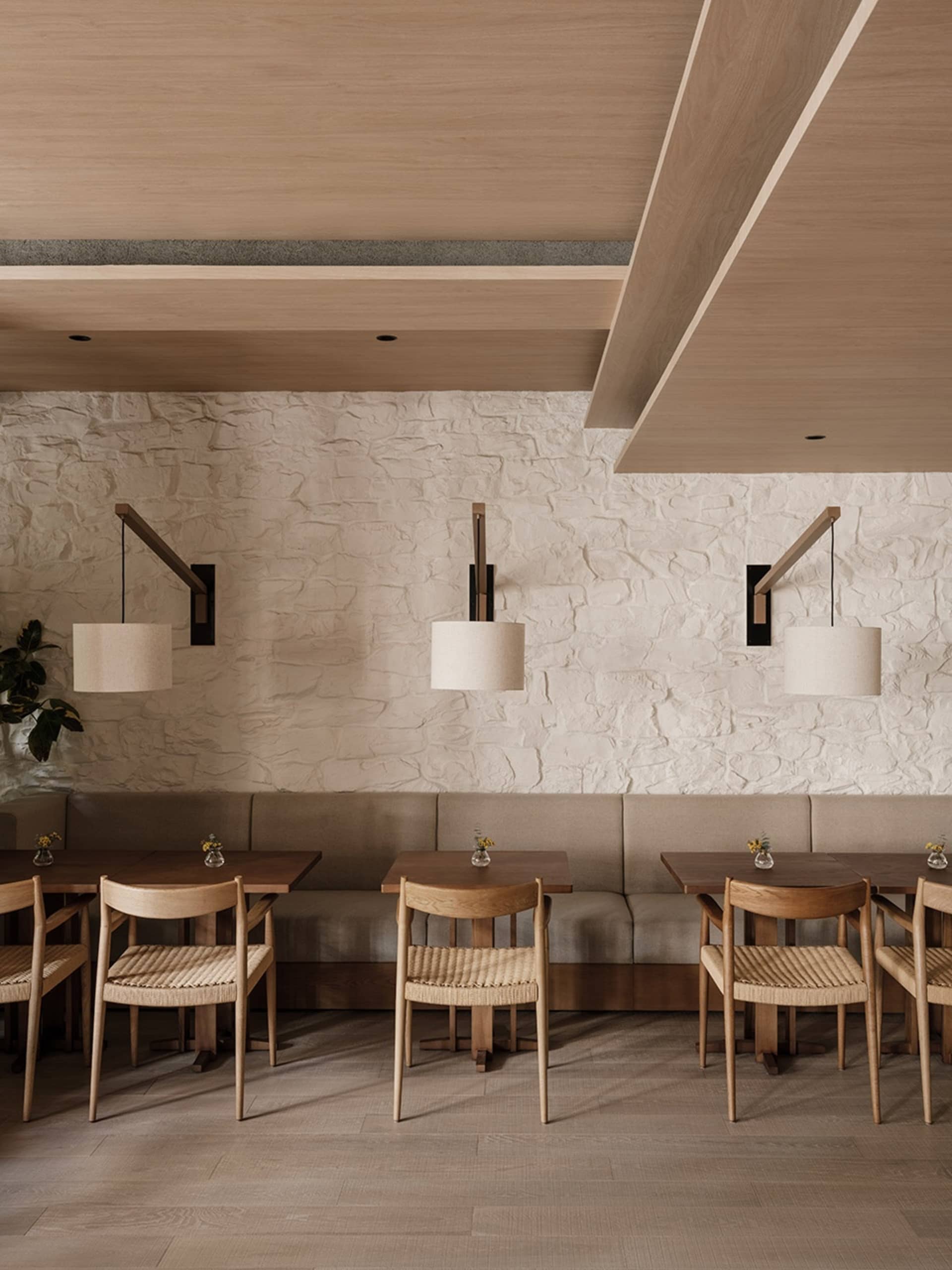 A photograph of a modern restaurant interior with wooden furniture and stone walls.