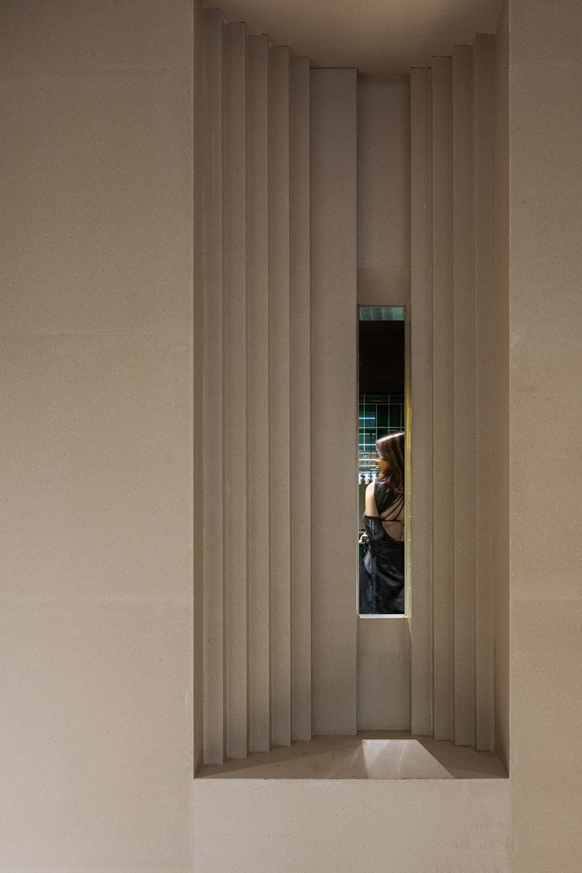 A modern interior design featuring a prominent concrete column with vertical stripes and a window detail.