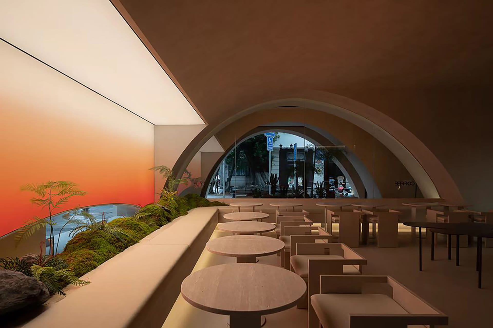 A modern restaurant interior with concrete texture walls and arches, featuring round tables and a living green wall.
