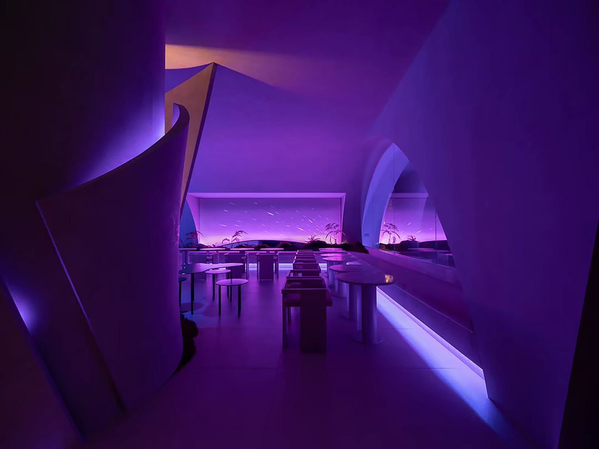 Interior of a minimalist restaurant featuring glass walls and a seating area with purple lighting.