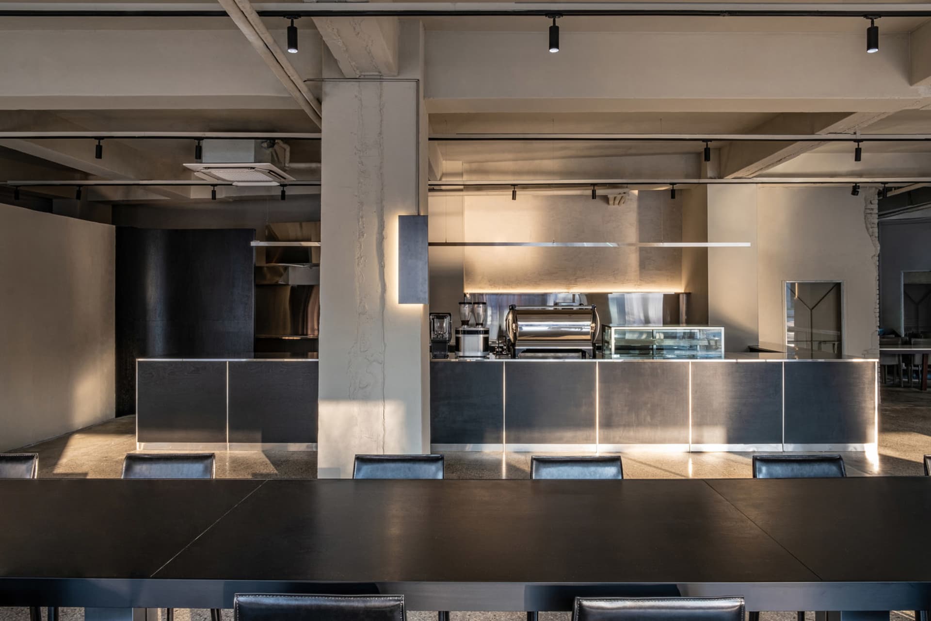 Modern cafe interior featuring a sleek metallic gray kitchen counter with a black top.