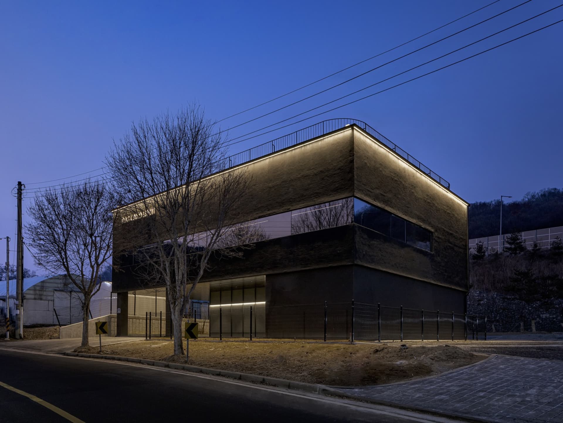 Modern office building with concrete exterior and illuminated roof.