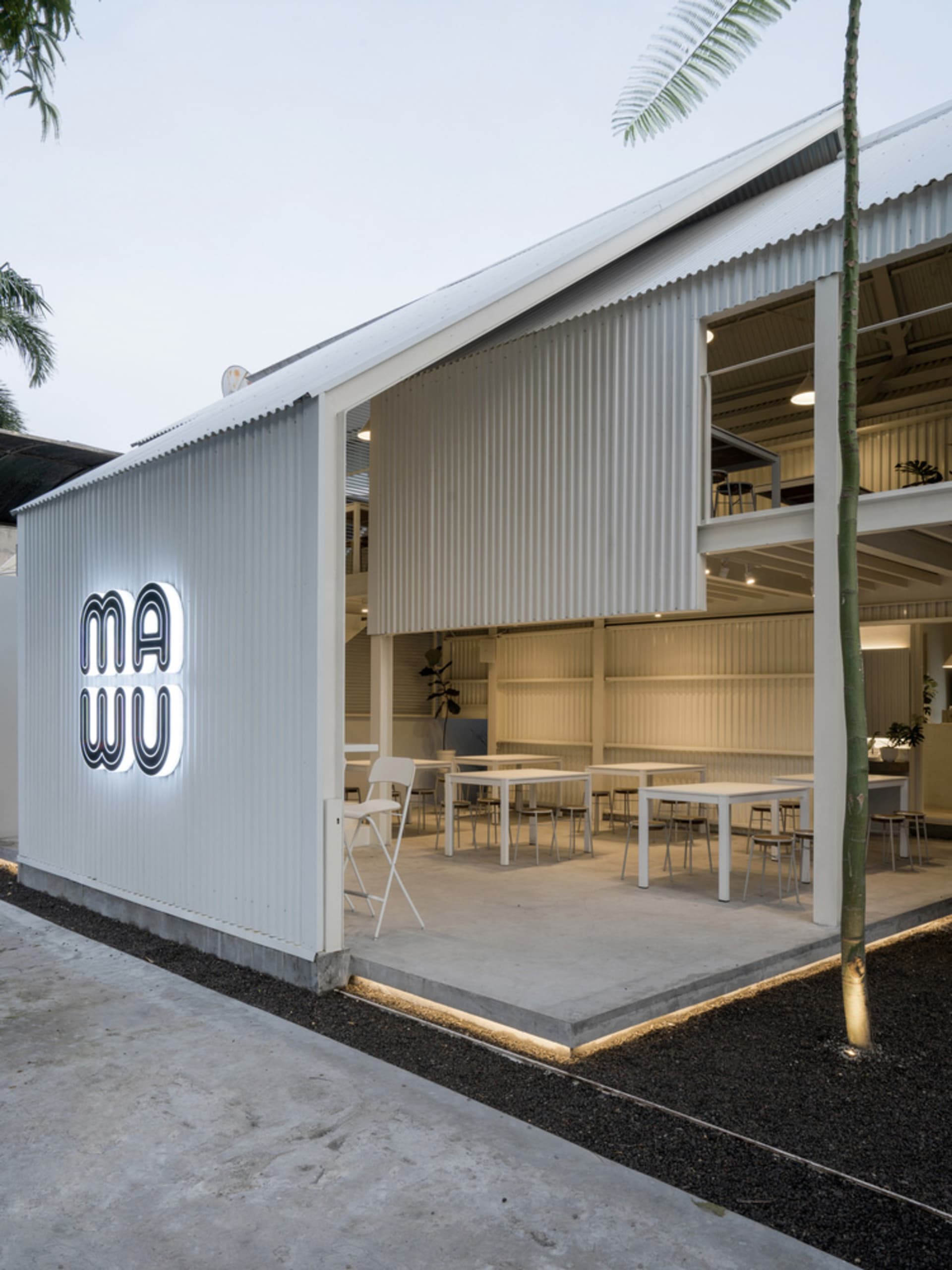 Modern industrial restaurant exterior with corrugated metal walls and open-air seating area.