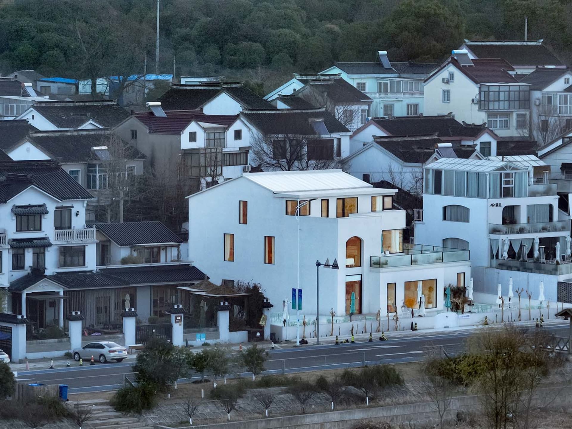 A modern white house with multiple levels and large windows.