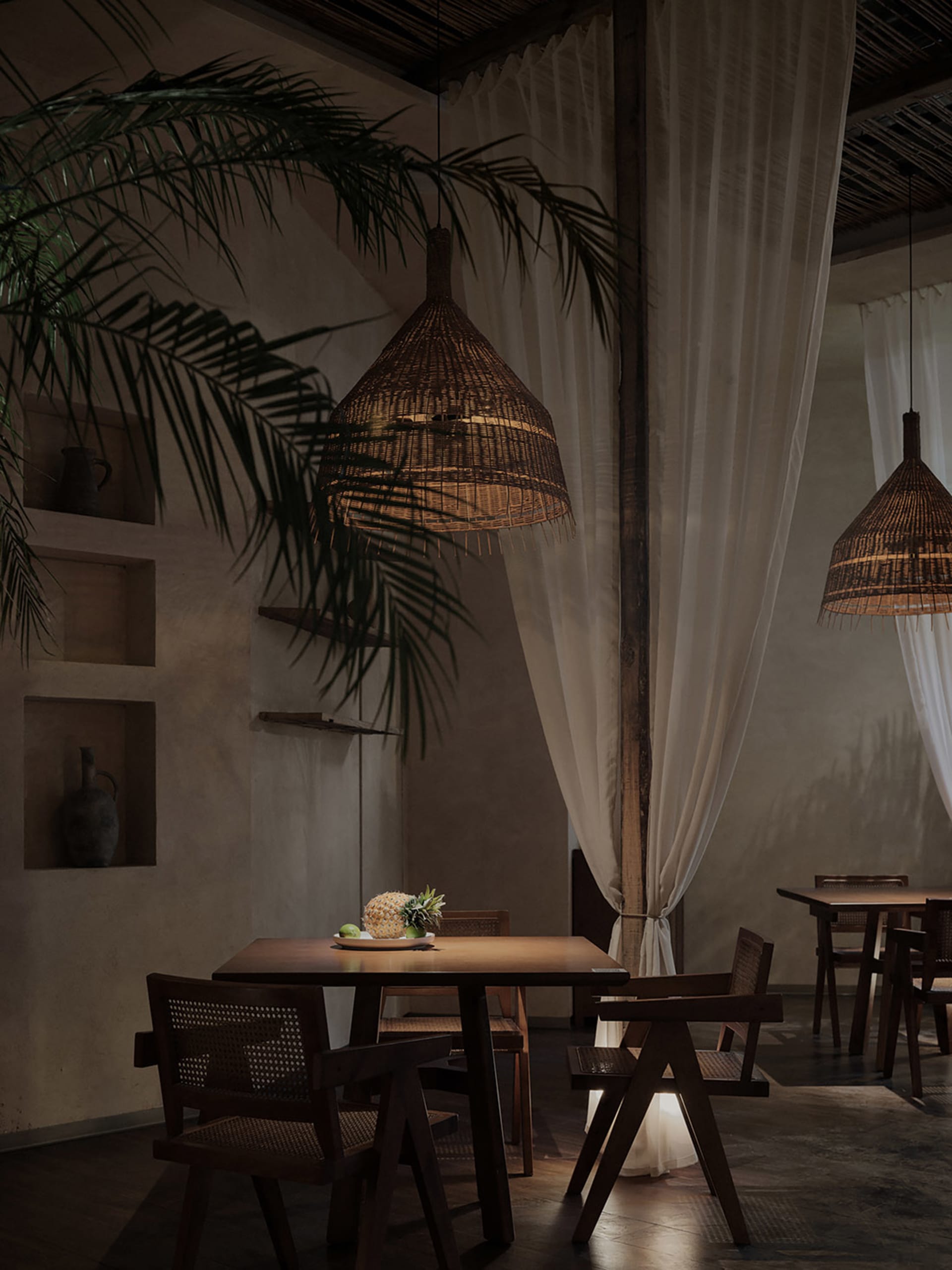 A rustic restaurant interior with wooden furniture, hanging wicker lights, and minimalist decor.