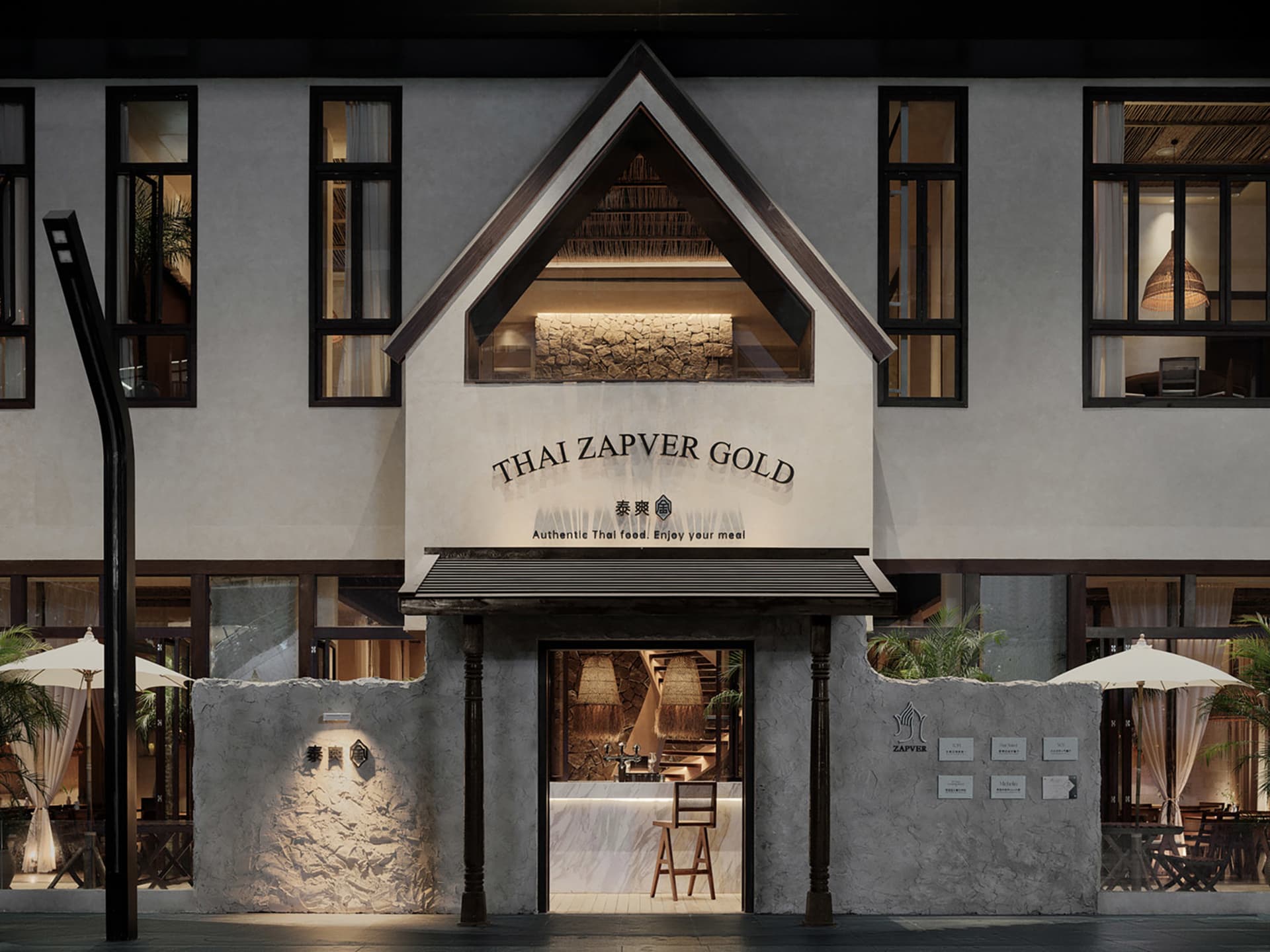 Exterior of a Thai restaurant with a plaster finish, wooden accents, and large windows.