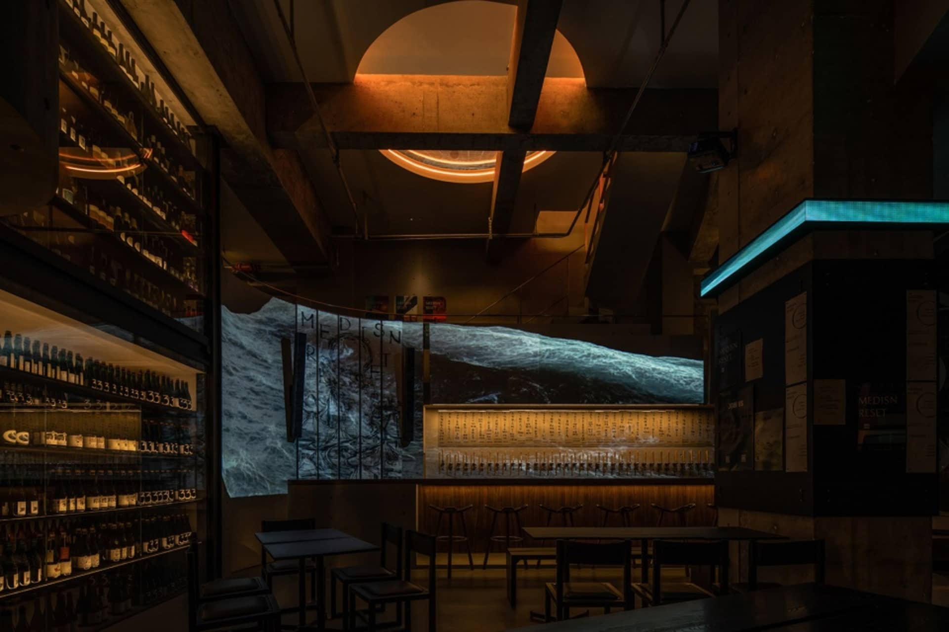 A modern bar interior with a concrete counter and illuminated lighting fixtures.