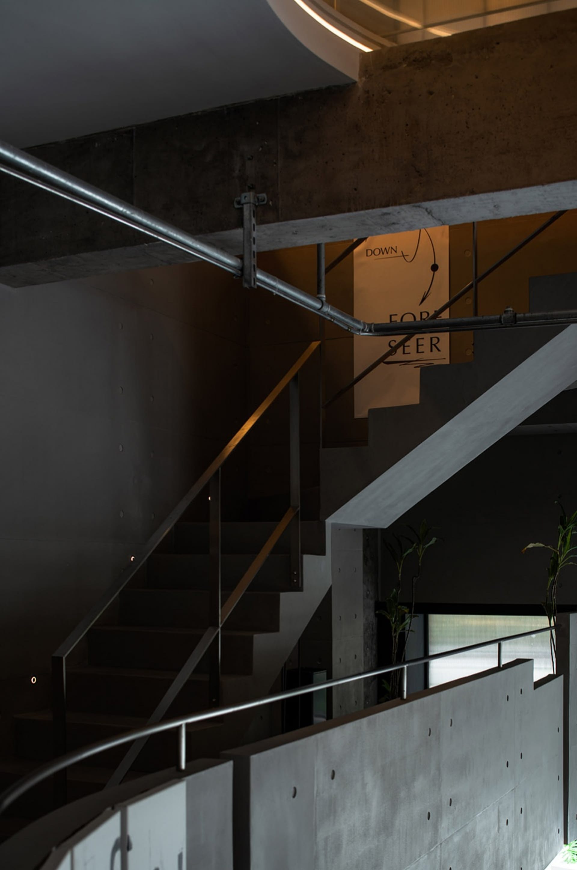 Modern industrial-style staircase with exposed concrete walls and floors, featuring minimalist design elements.