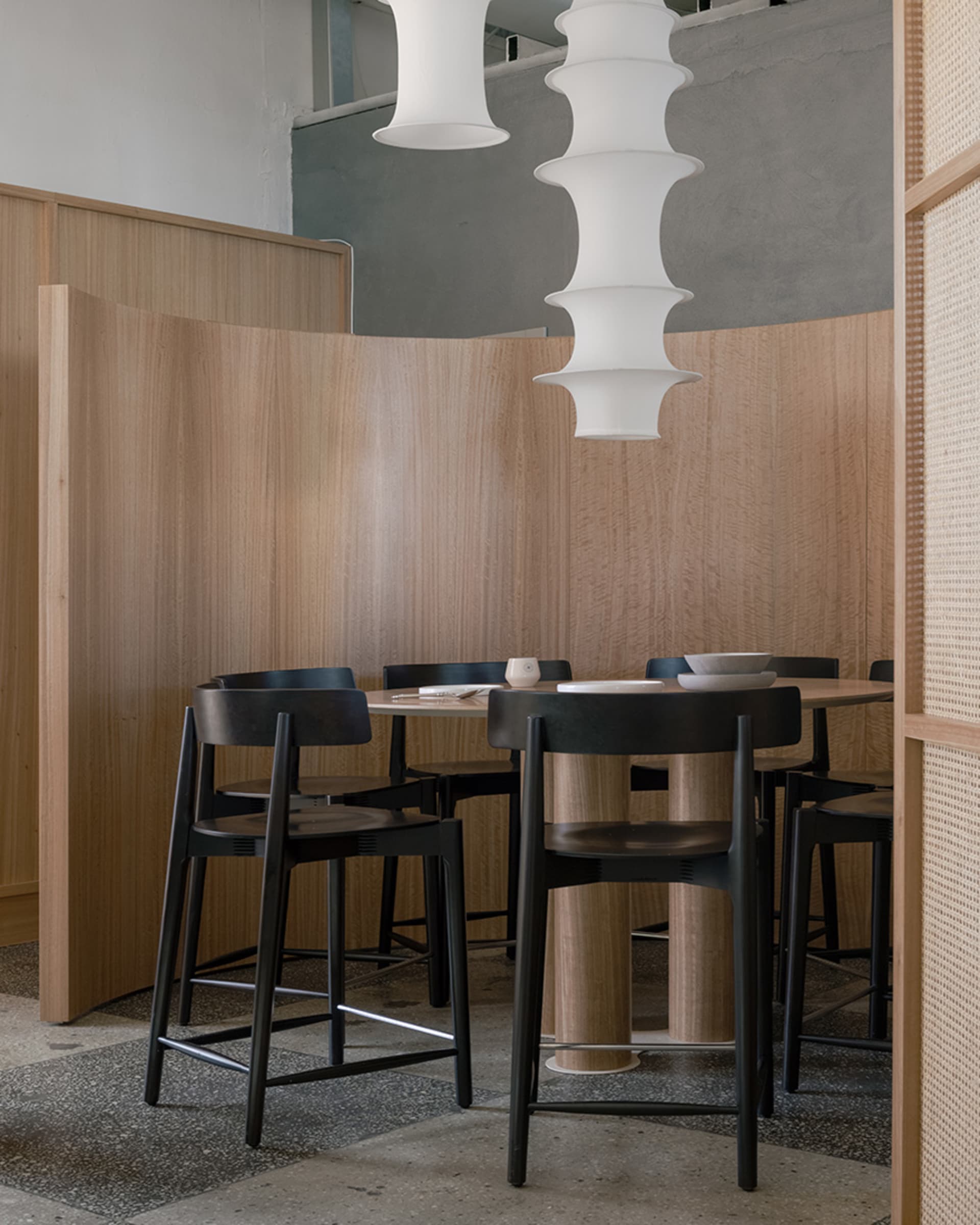A modern restaurant interior featuring wooden tables and chairs in a cozy setting.