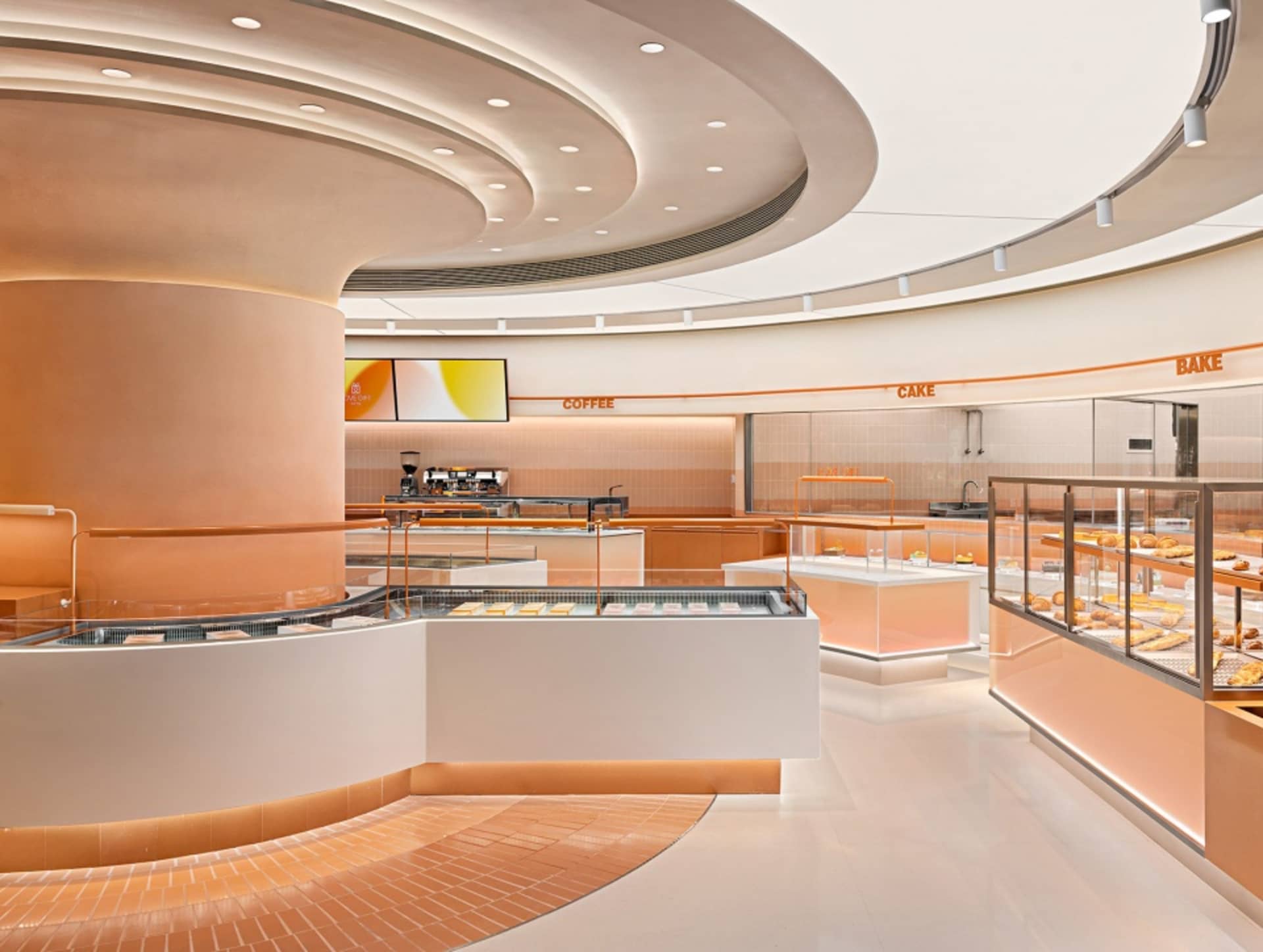 A modern cafe interior with orange accents and white marble counters.