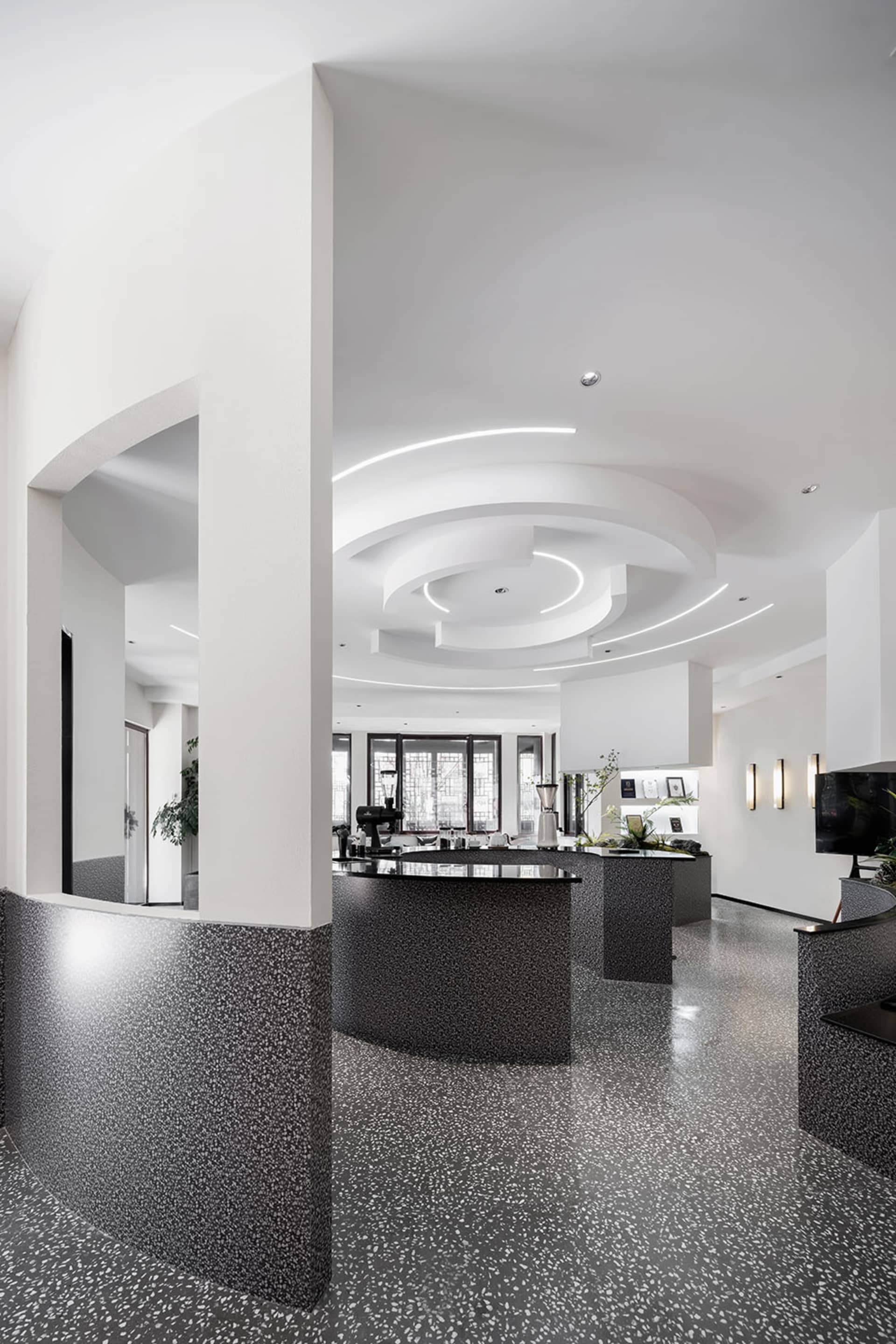 Modern restaurant interior with terrazzo flooring, minimalist design, and sleek black and white decor.