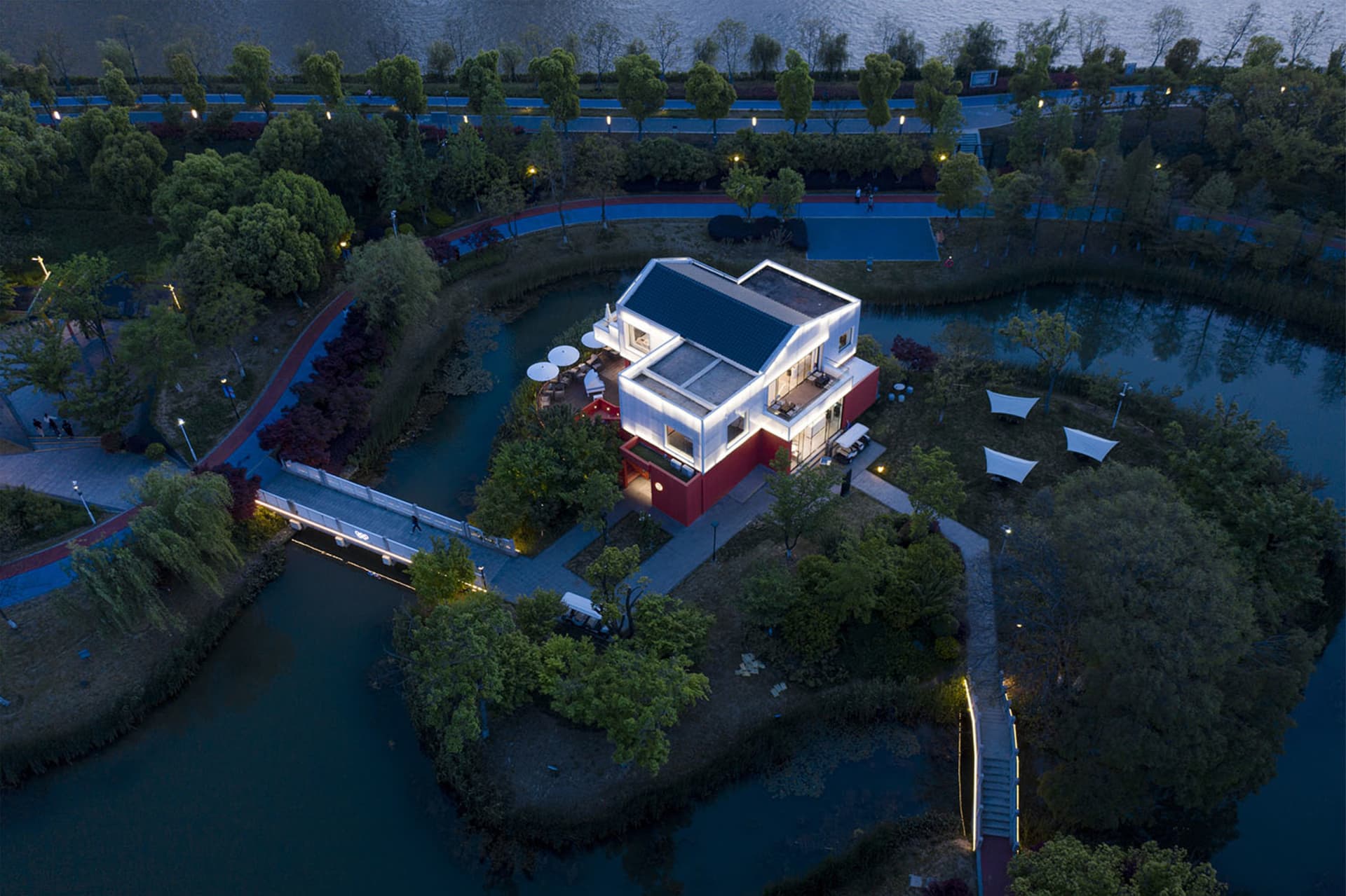 一棟現代住宅被樹木環繞,夜燈照亮公園環境。