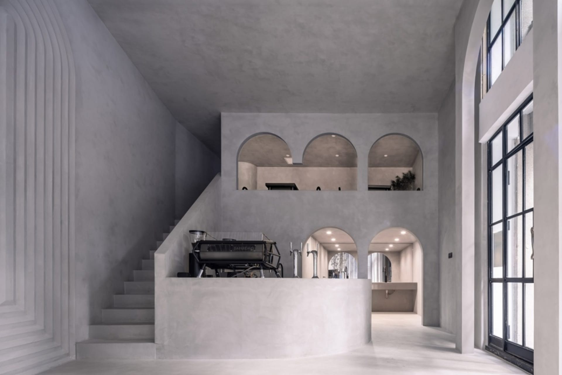Modern coffee shop interior with concrete walls and floors, featuring minimalist design and industrial elements.