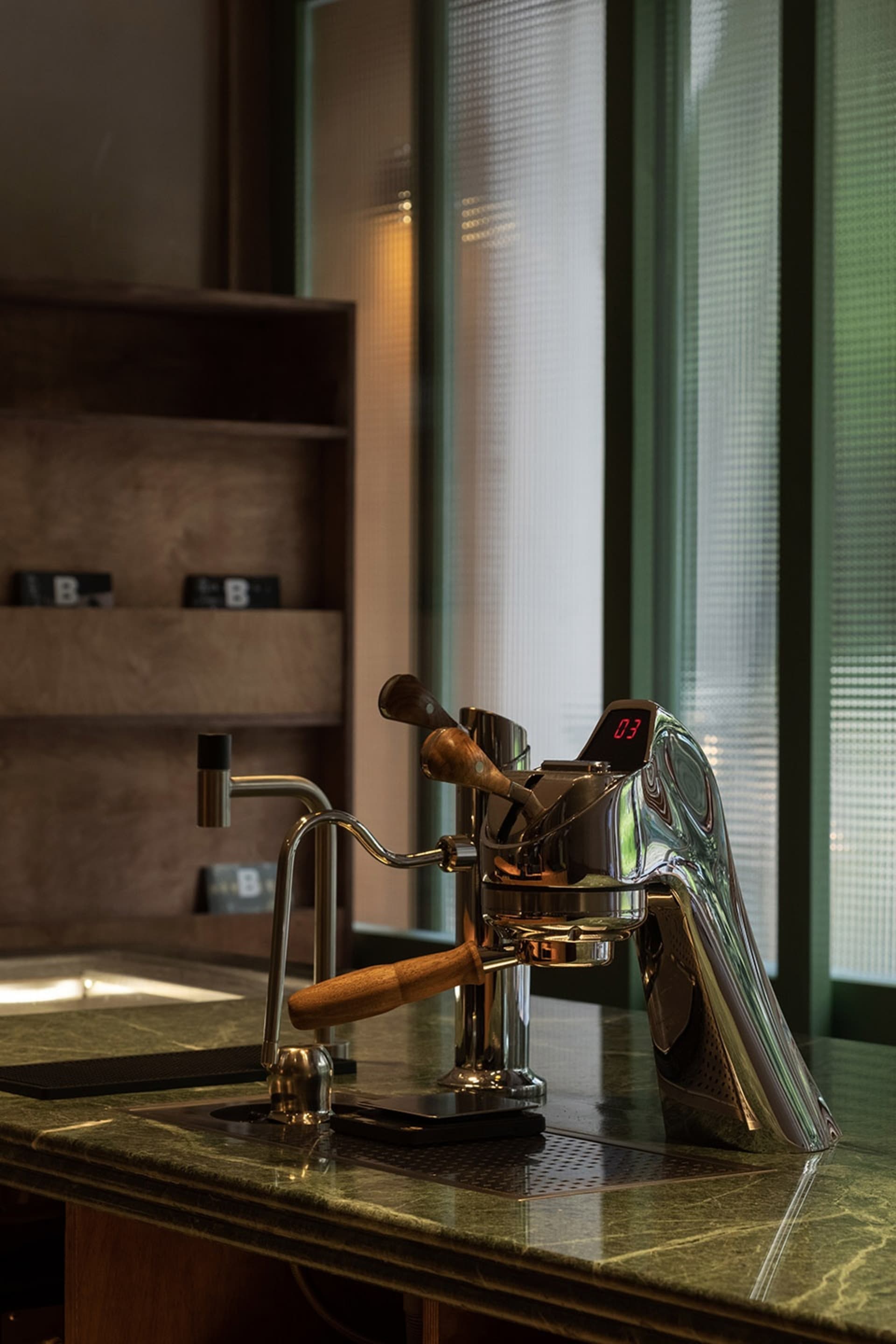 A sleek, metallic espresso machine in a contemporary coffee shop setting.