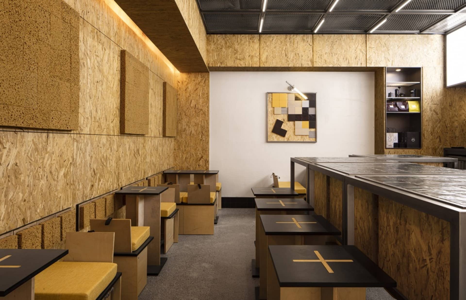 Interior view of an industrial-style cafe with tables, chairs, and a counter made of OSB board and metal