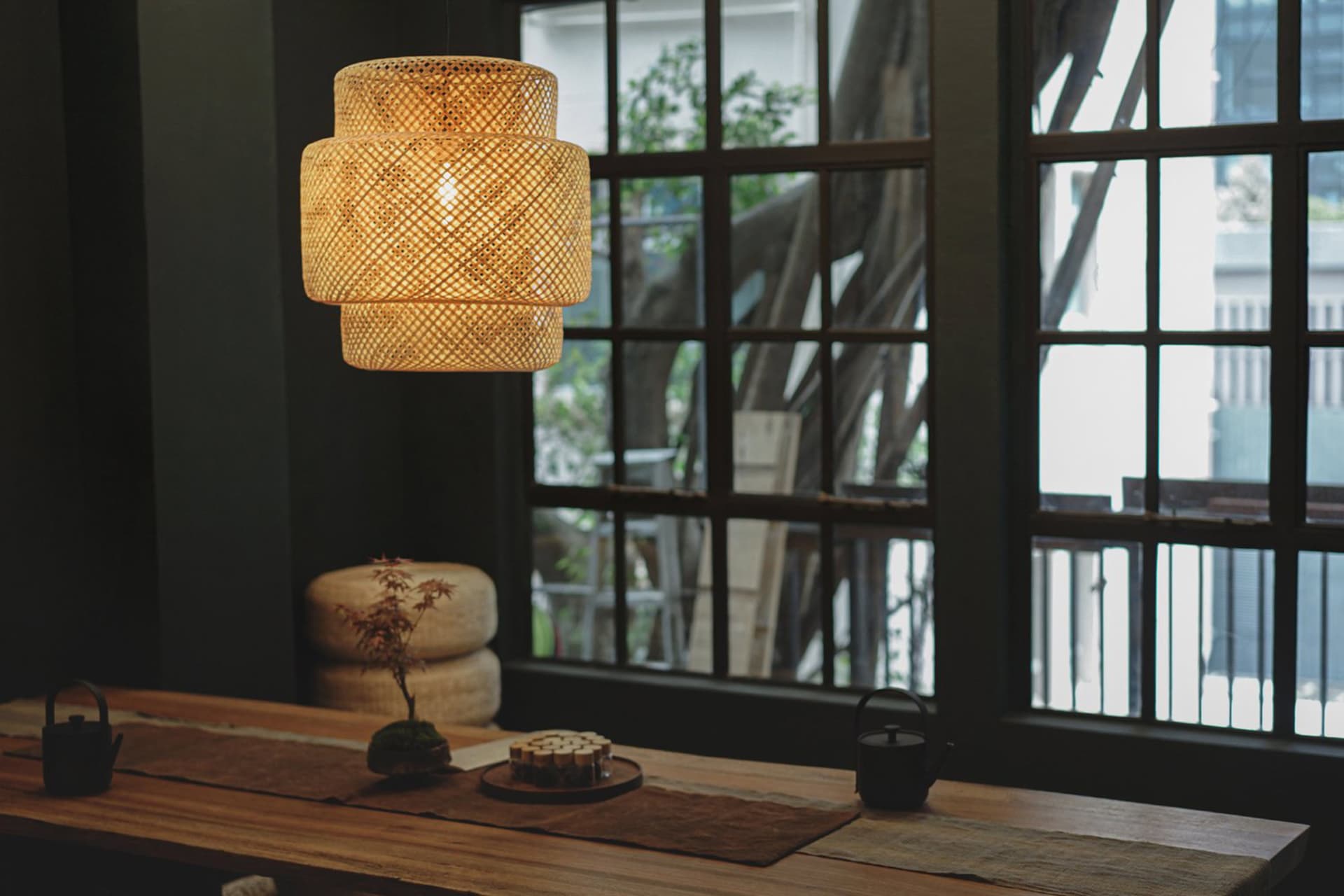 A hanging bamboo ceiling light in an industrial living room setting.