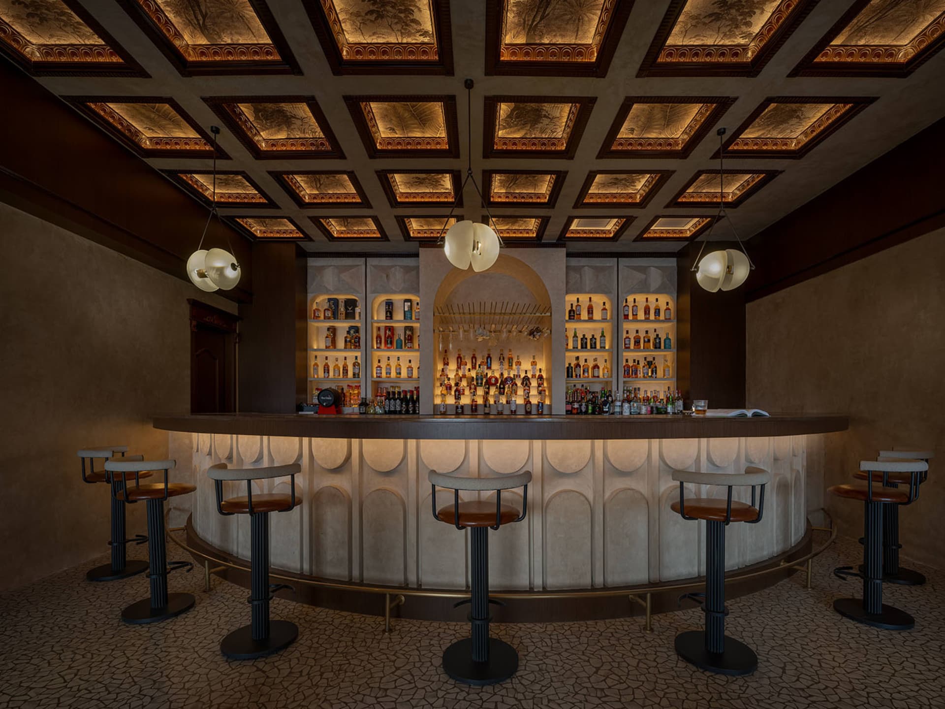 A luxury bar interior featuring a sleek, modern concrete counter with bar stools, illuminated shelves, and a sophisticated ce