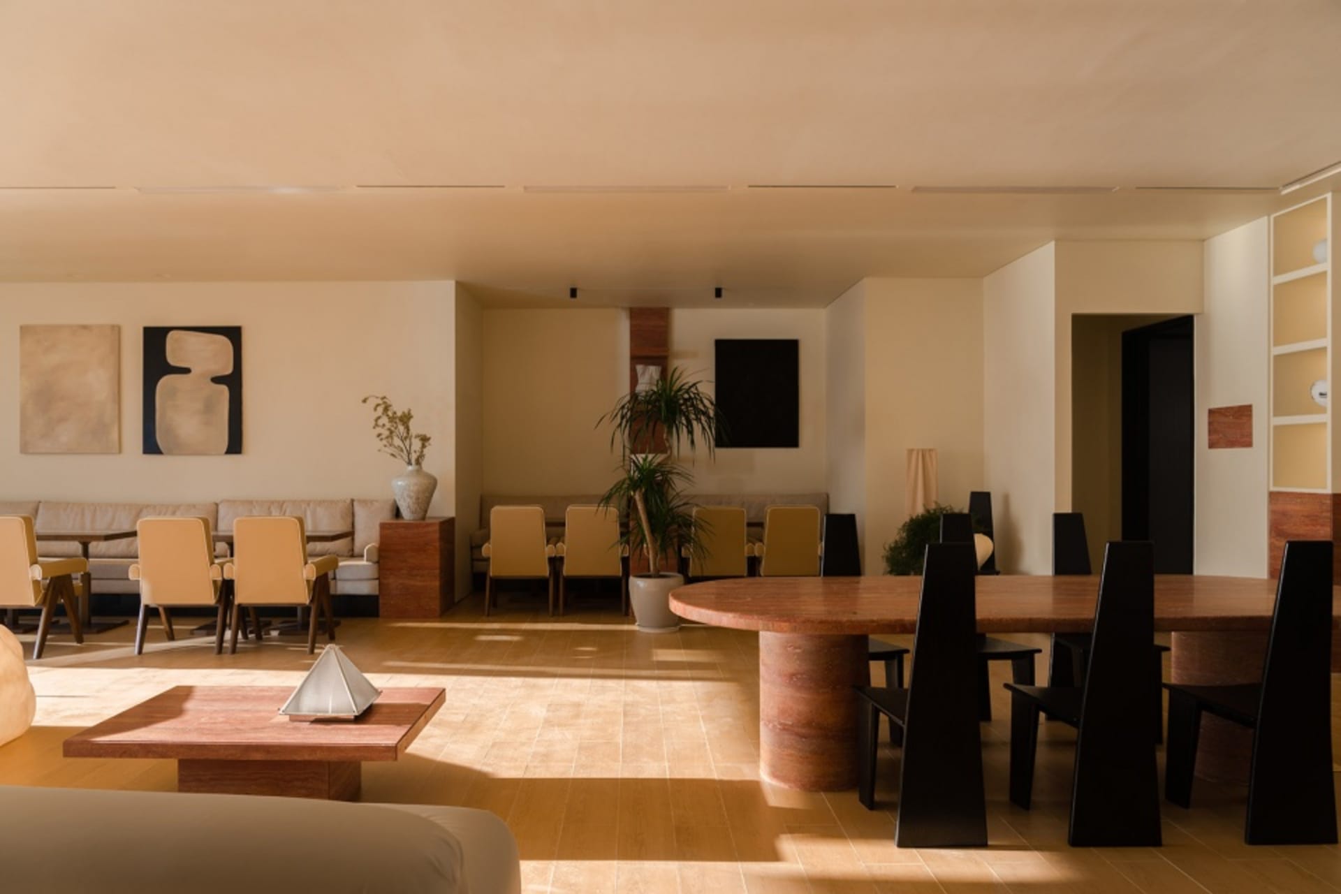 A modern living room with neutral tones, featuring multiple seating arrangements and a wooden table.