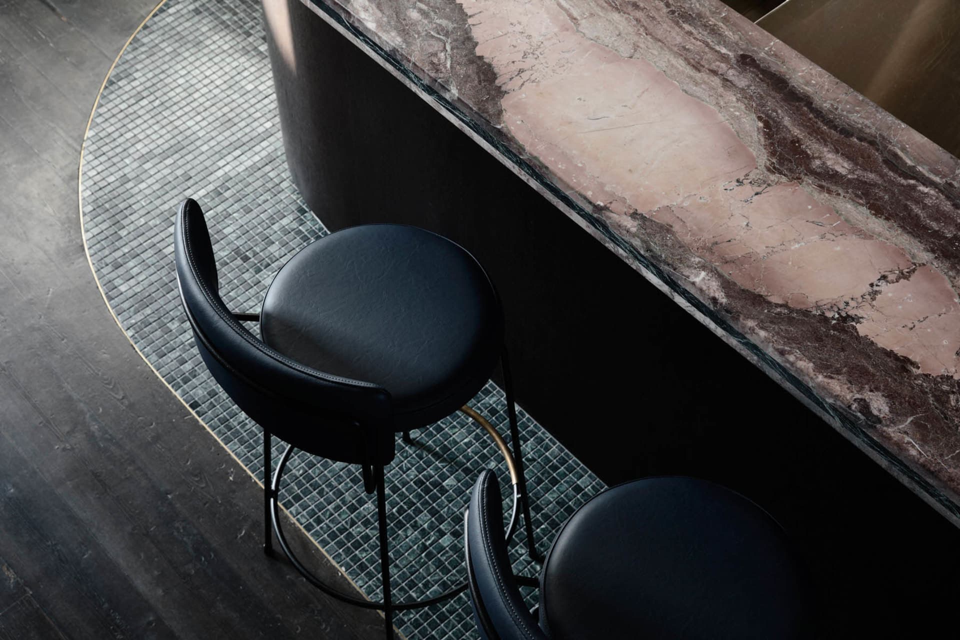 Modern bar counter made of marble with black leather stools