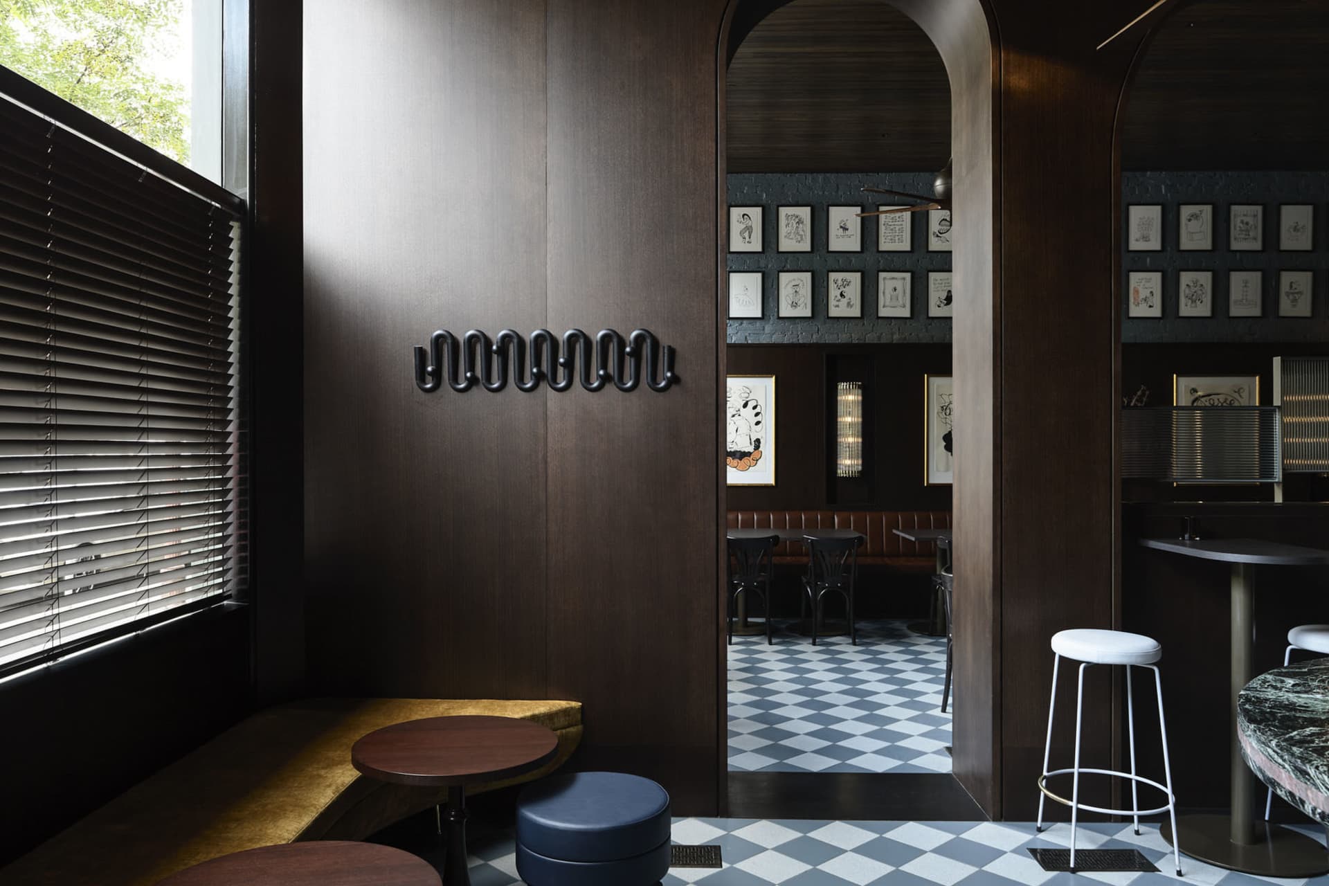 Modern restaurant interior with wooden seating, marble tables, and checkered-tiled floor.