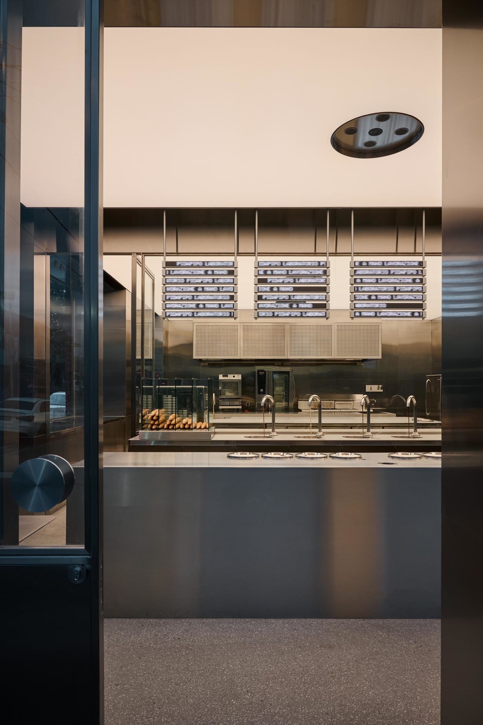 A modern restaurant with a metallic counter and glass display case.