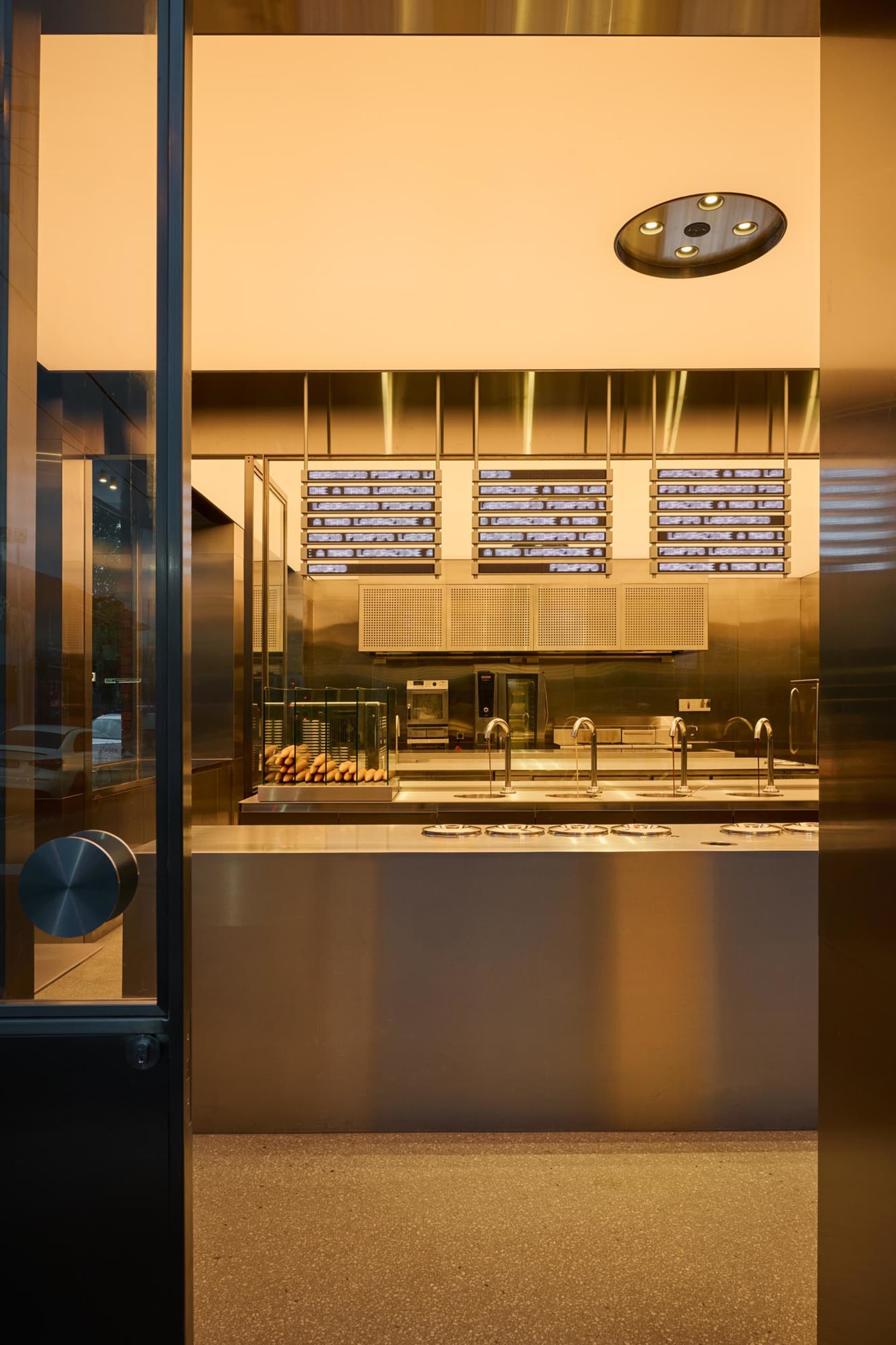 A modern storefront with a metallic glass door, featuring illuminated signage and sleek design elements.