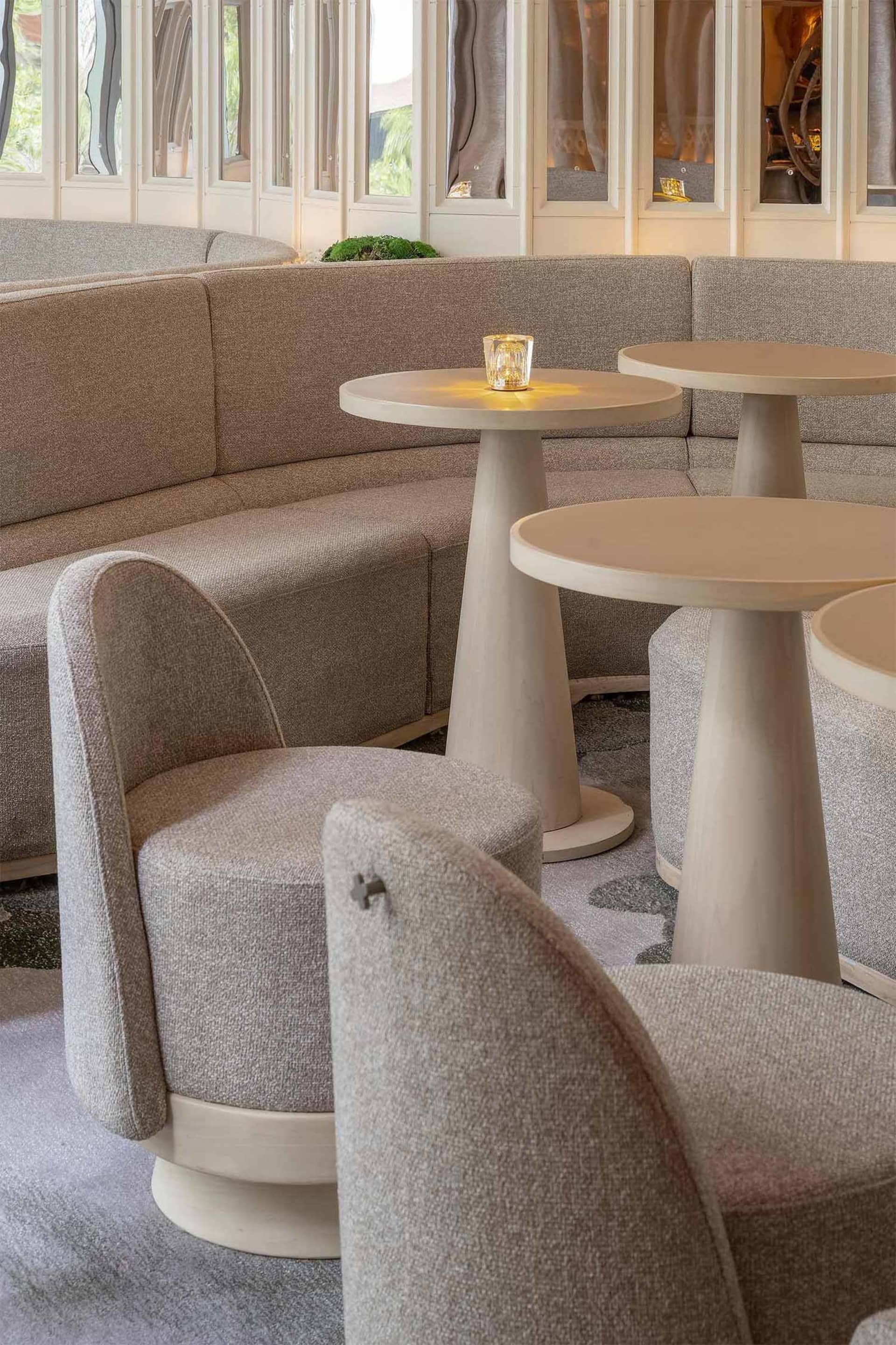 Modern restaurant seating area with light-colored upholstered sofas and tables with minimalist design.