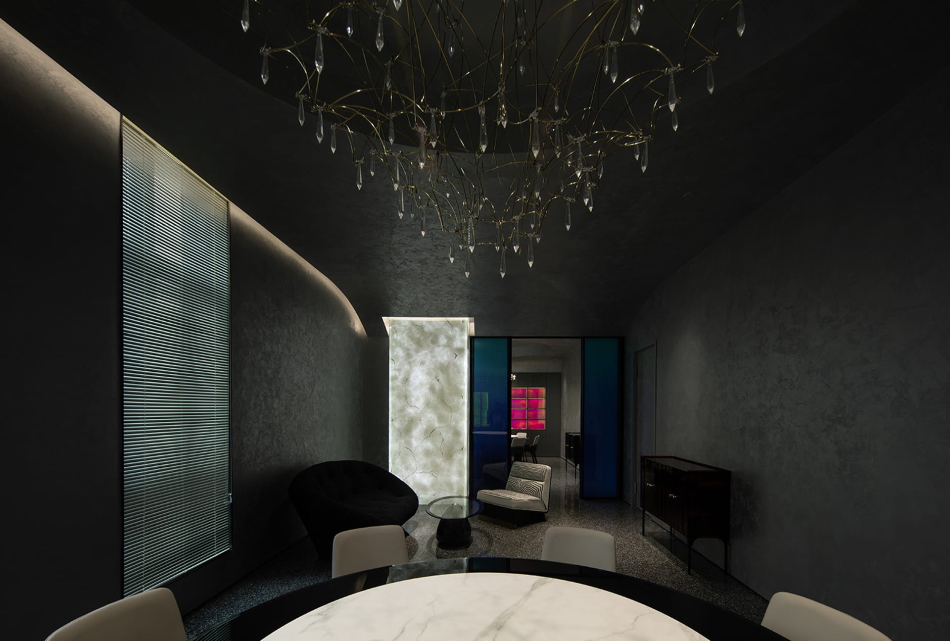Modern residential dining room with marble table, metal chandelier, and dark-colored walls.
