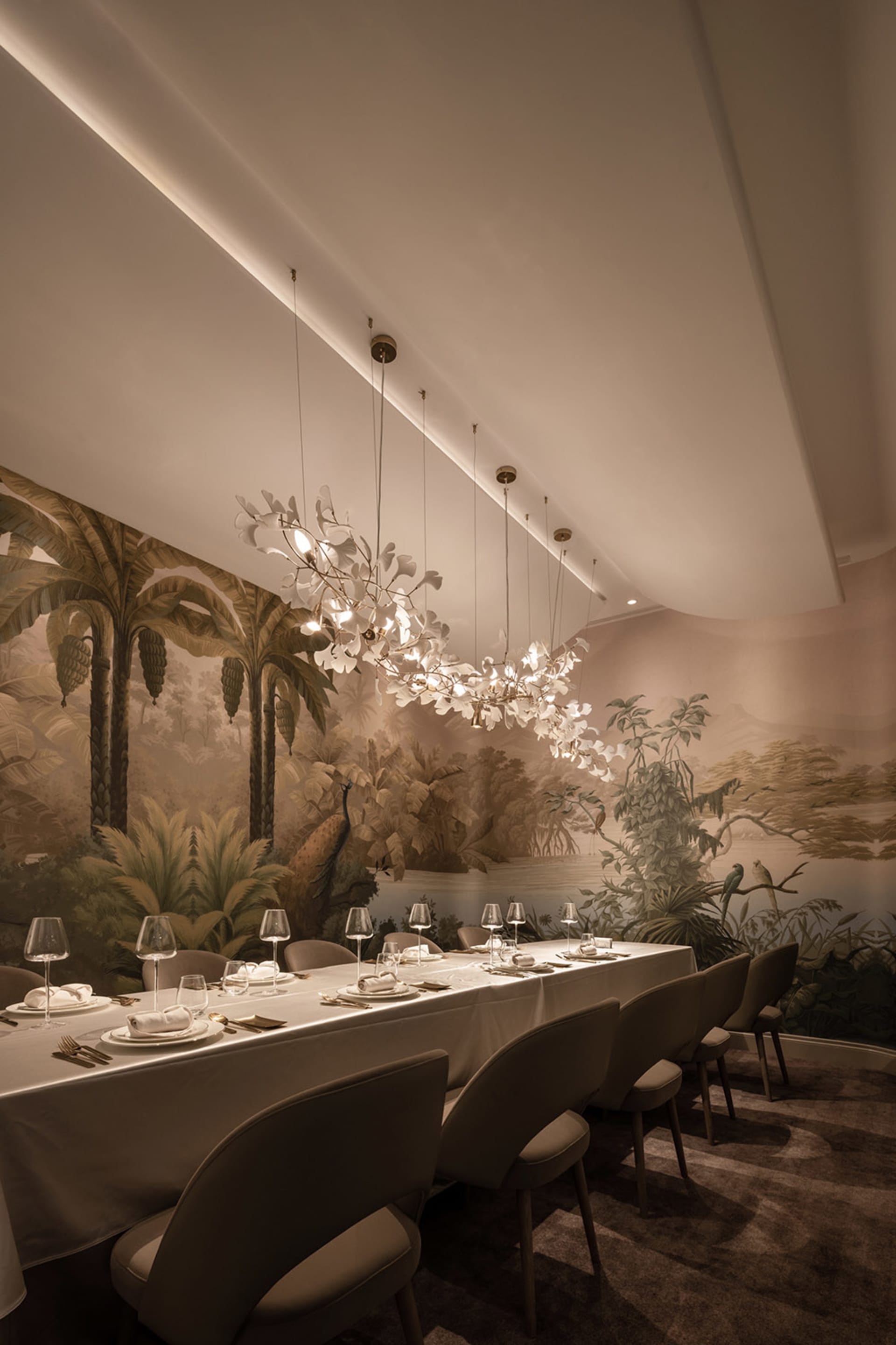An elegant restaurant dining room with a jungle-themed mural, plush seating, and elaborate lighting fixtures.