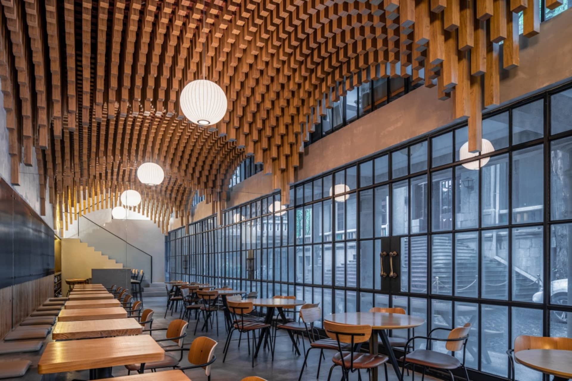 現代木質餐廳室內,懸掛燈具與大型窗戶。