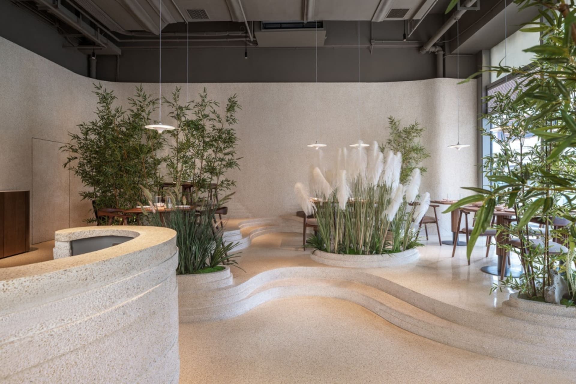 Interior view of a modern cafe with concrete flooring and potted plants.