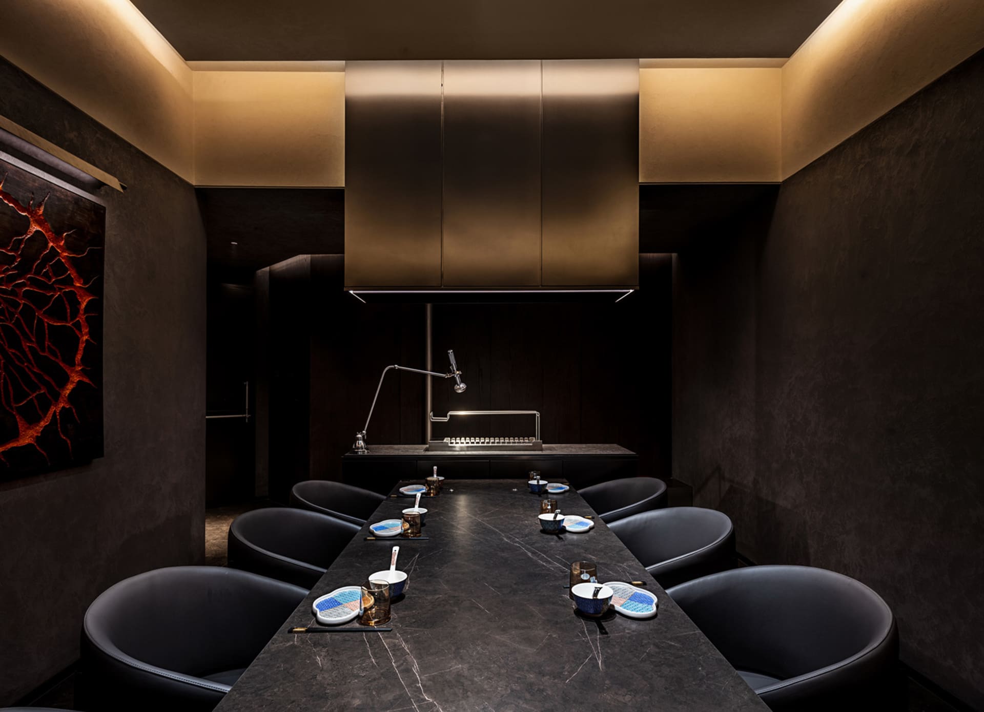 A sleek, modern kitchen with concrete walls, a dark countertop, and minimalist decor.