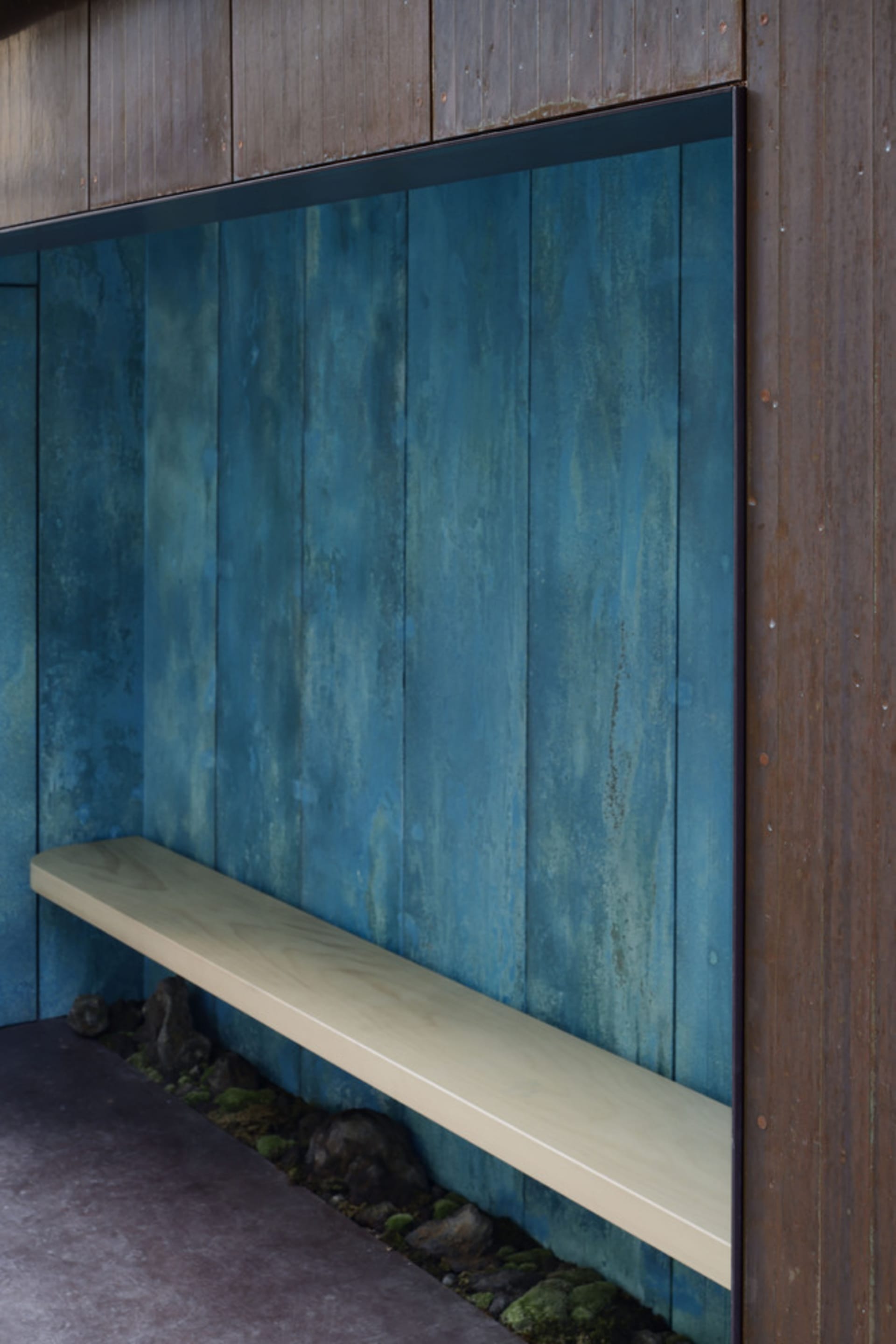 A minimalist interior design featuring a wooden bench and blue wooden walls.