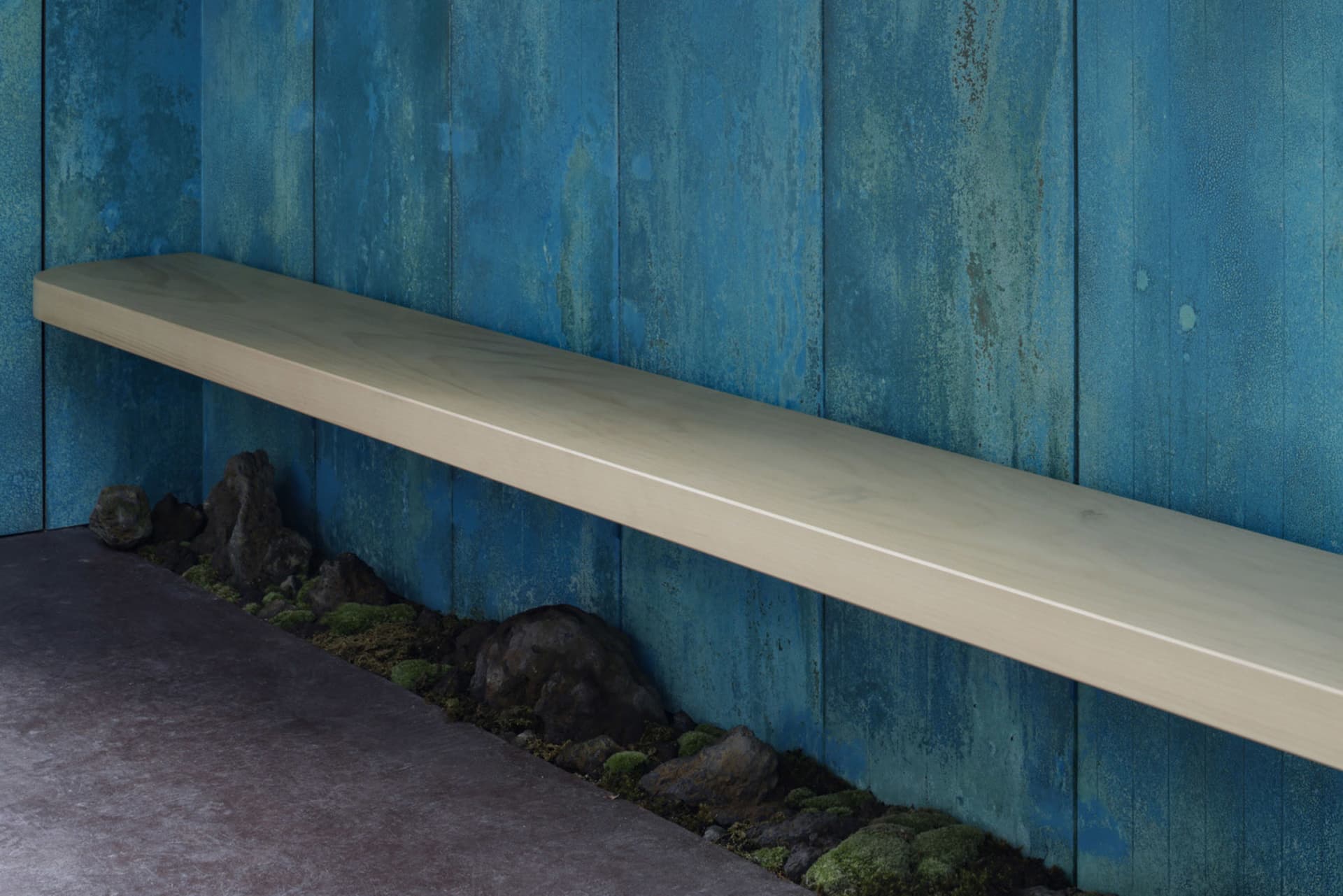A minimalist floating shelf mounted on a blue wall with a textured surface.